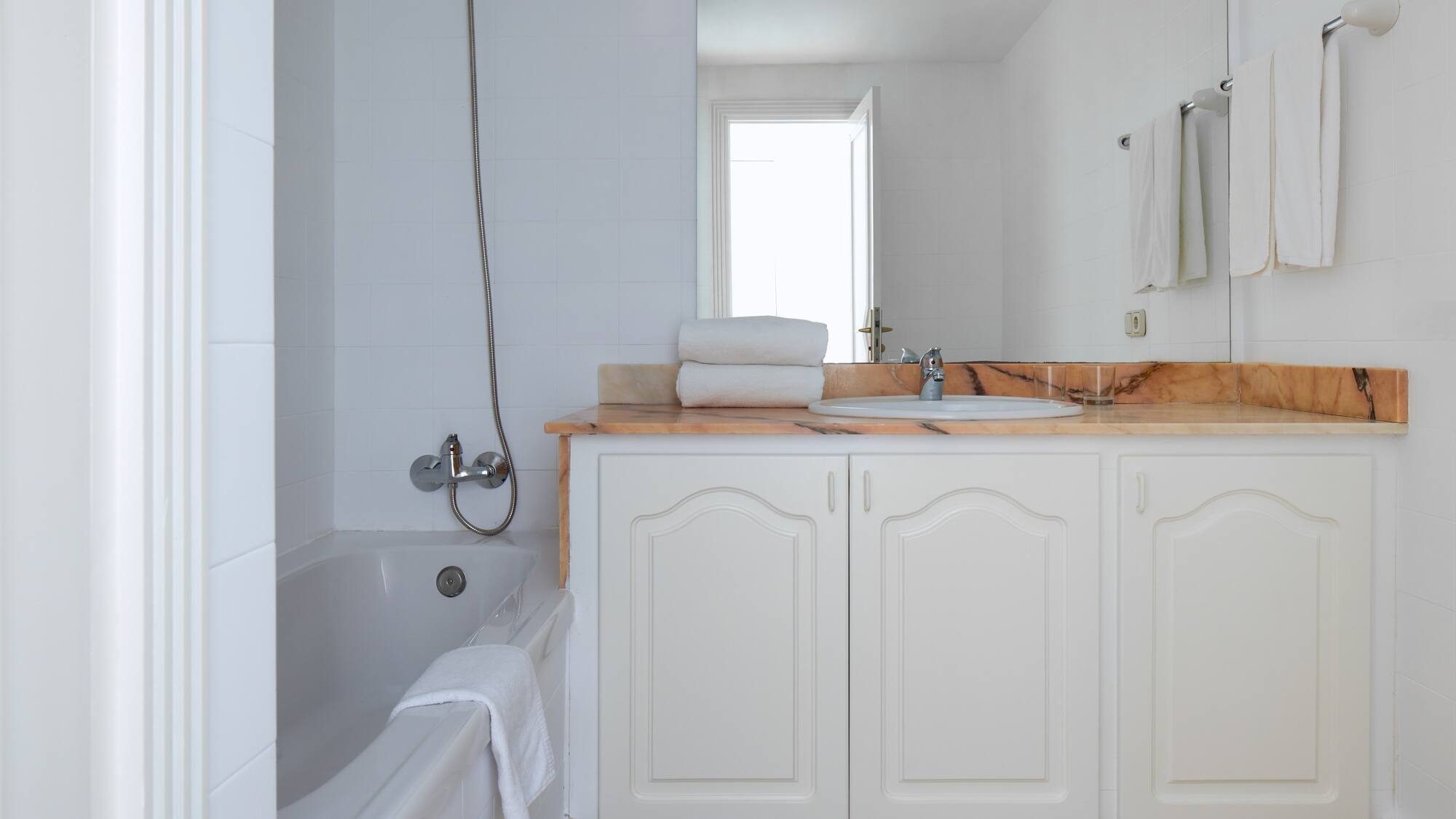 a bathroom with white cabinets and a bathtub