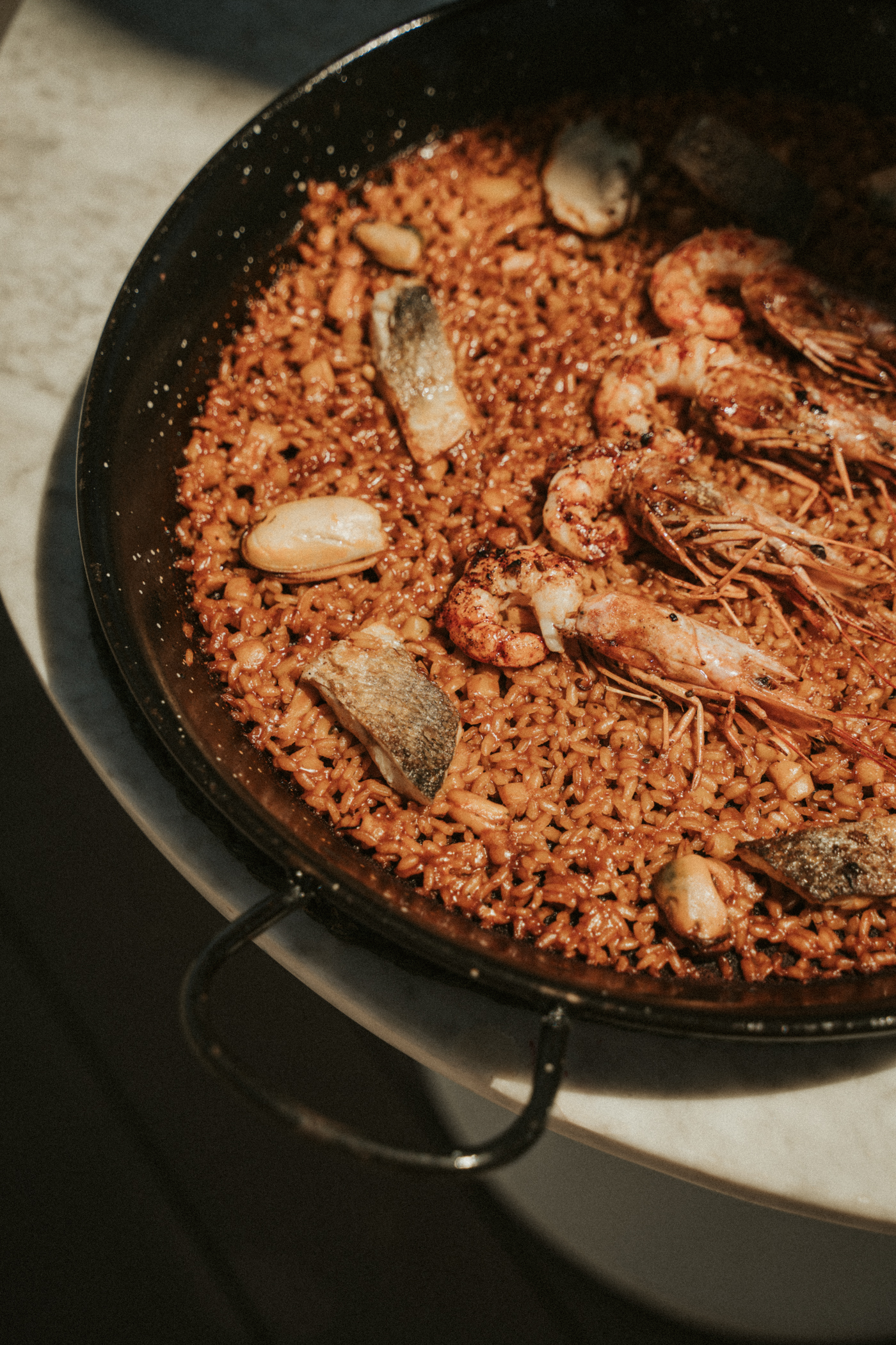 Spanish seafood paella in black paella pan with prawns, fish, and rice.