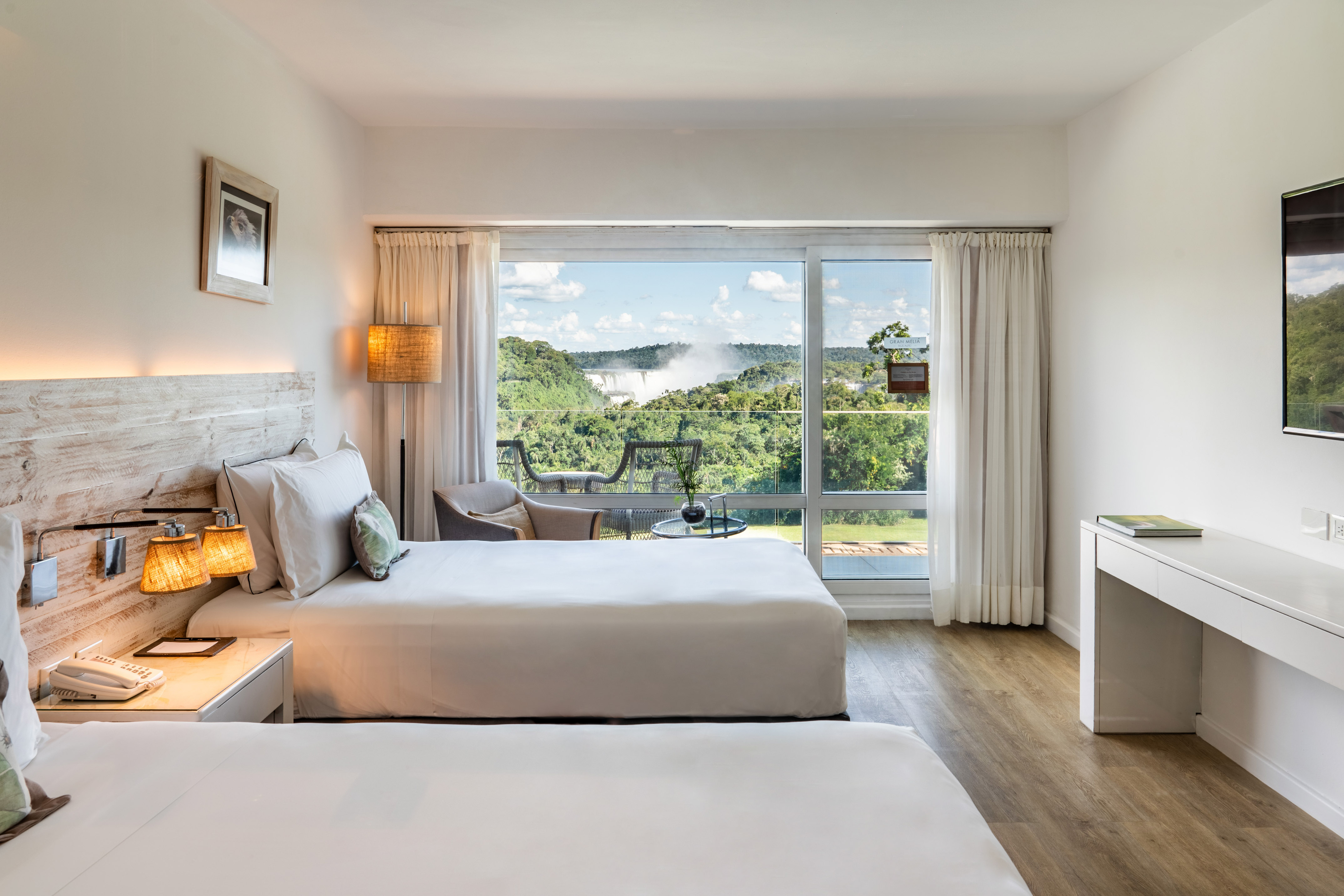 Hotel room with panoramic view of Iguazu Falls and dense rainforest.