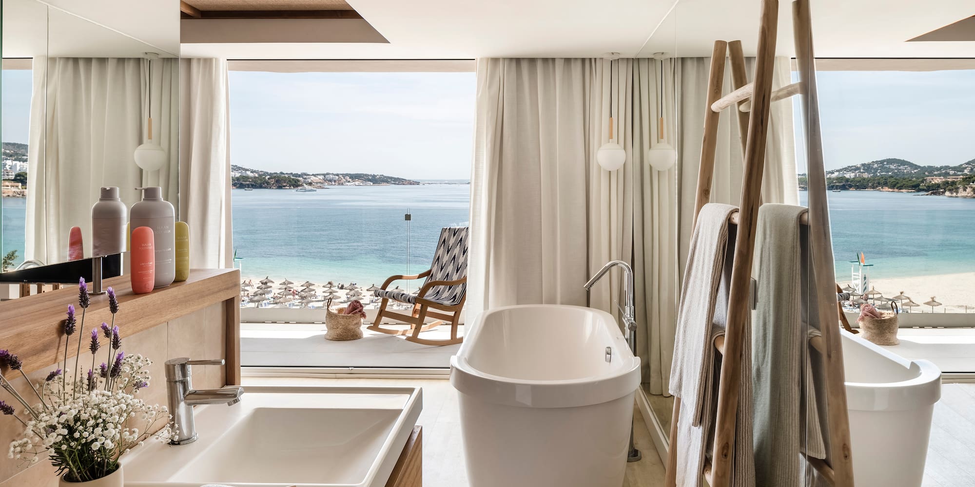 a bathroom with a tub and a shower and a chair overlooking the water