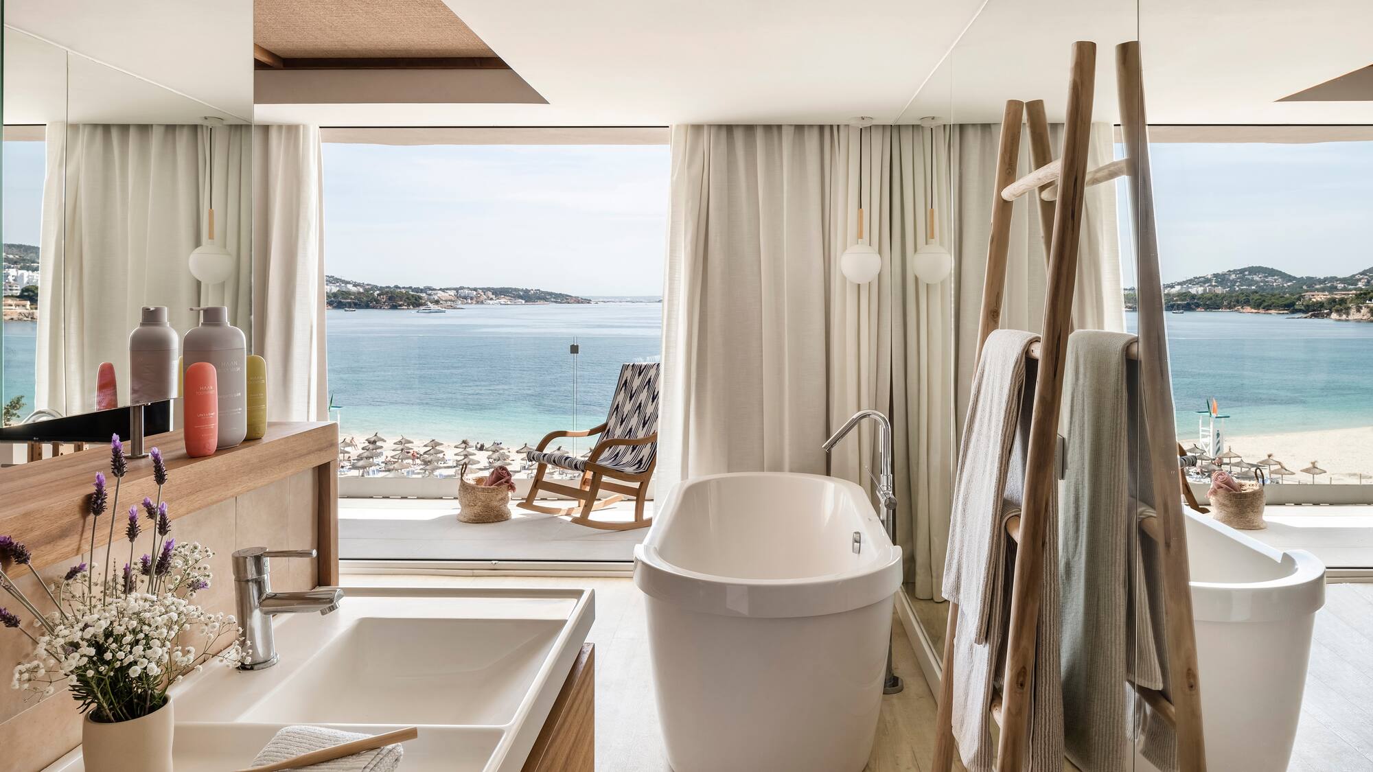 a bathroom with a tub and a shower and a chair overlooking the water