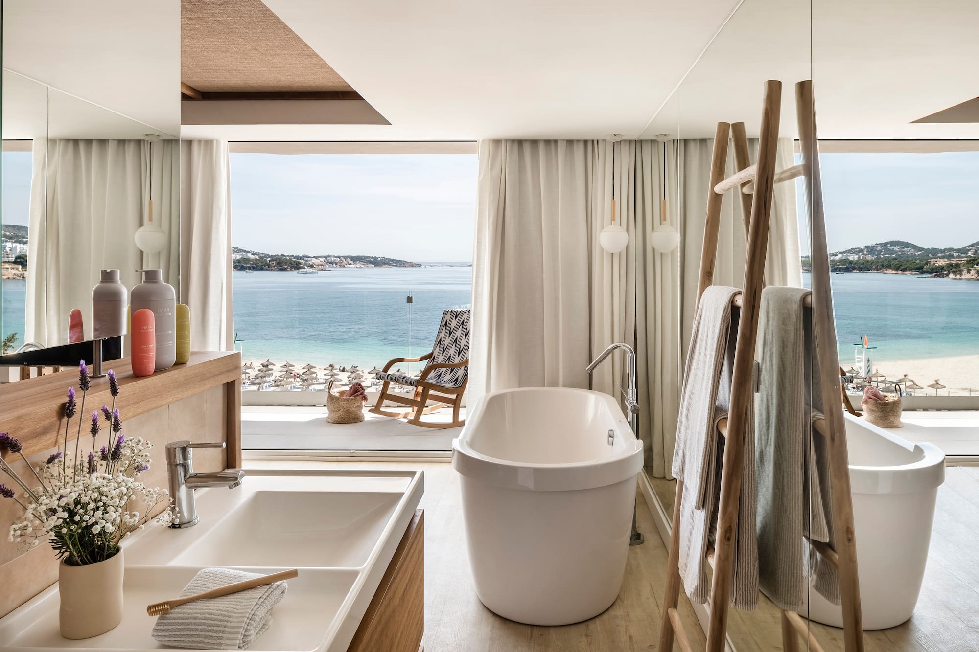 a bathroom with a tub and a shower and a chair overlooking the water