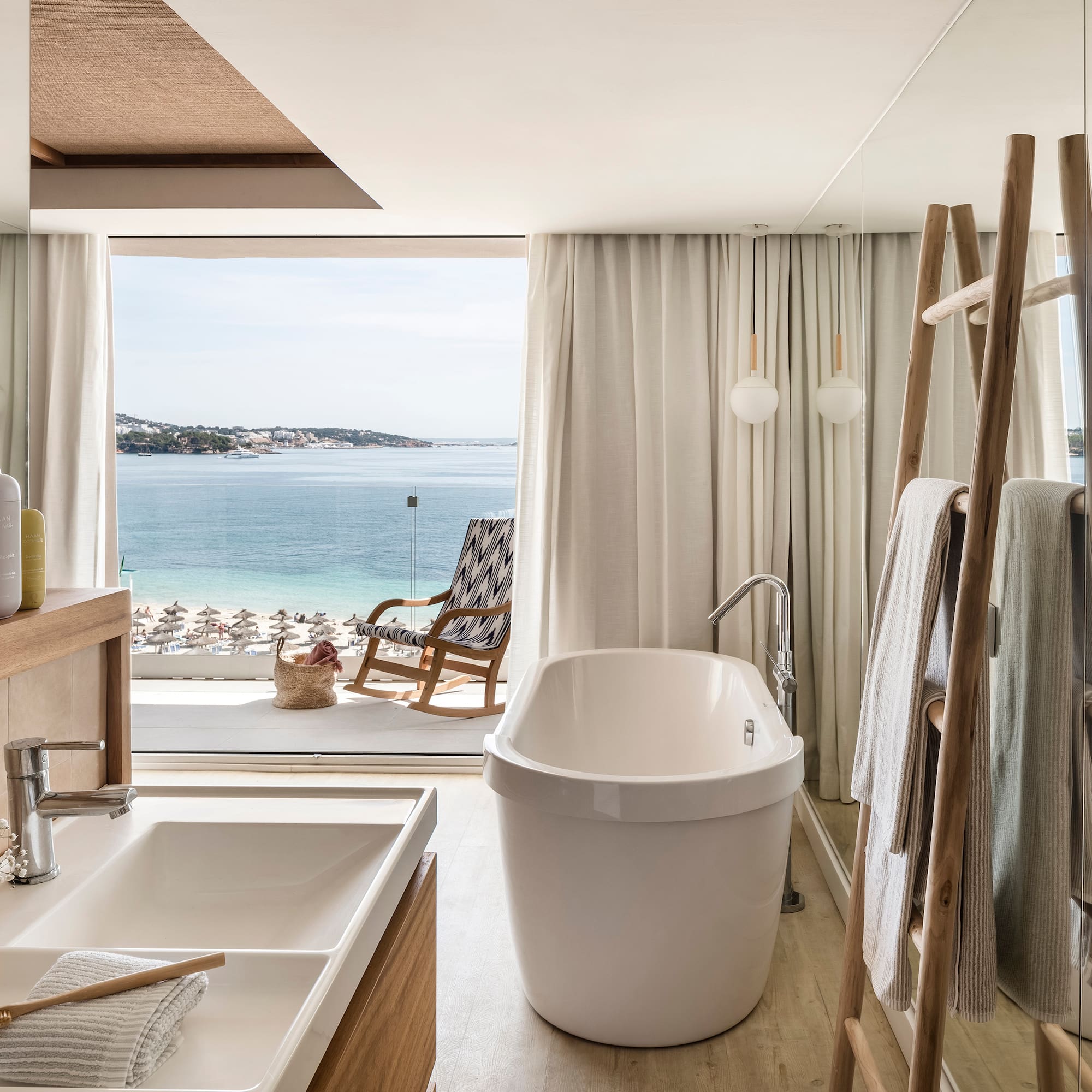a bathroom with a tub and a shower and a chair overlooking the water