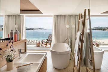 uma casa de banho com uma banheira, um chuveiro e uma cadeira com vista para a água
