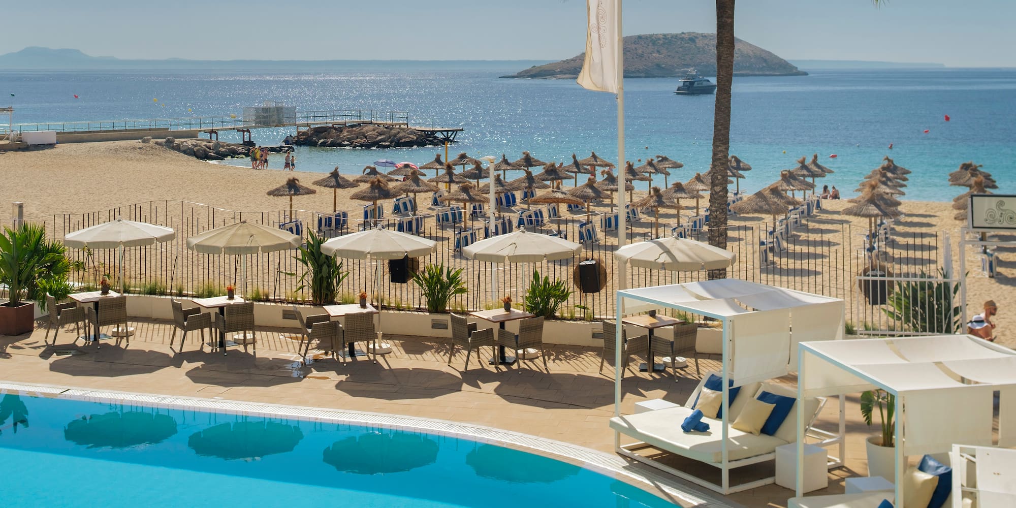 a pool with umbrellas and chairs on a beach