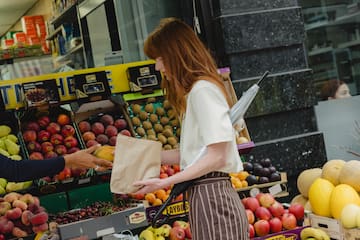 a woman standing in front of a fruit stand