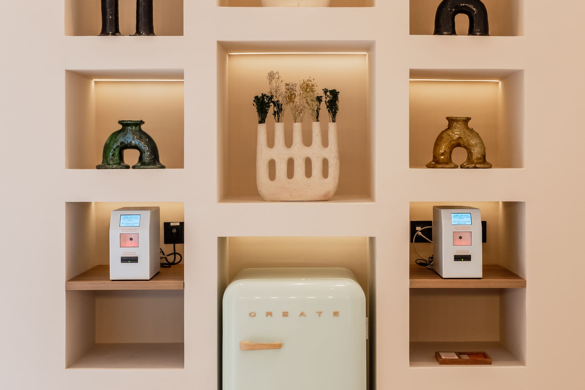 Built-in wall display with decorative vases, mint retro fridge, and smart tech.