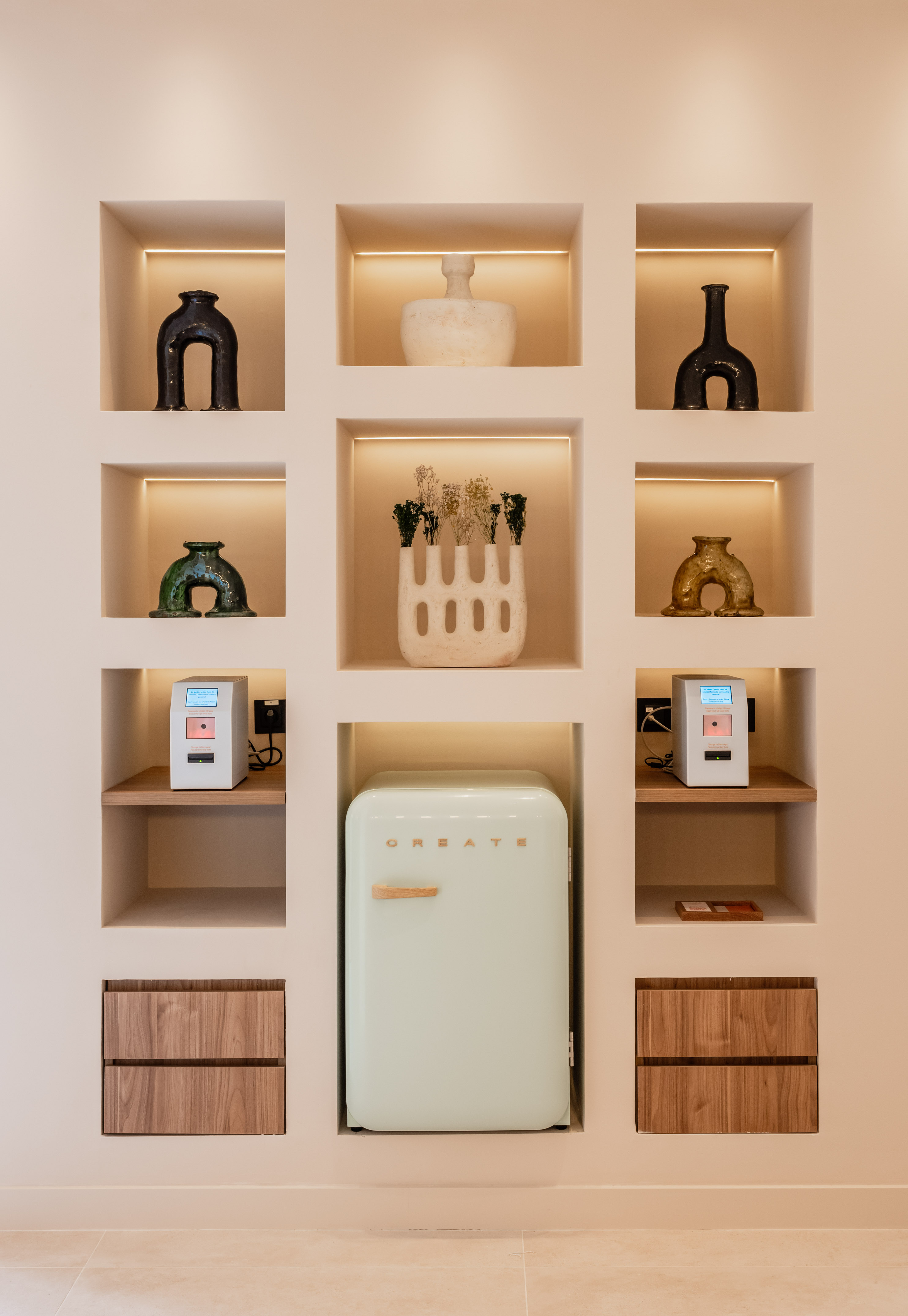Built-in wall display with decorative vases, mint retro fridge, and smart tech.