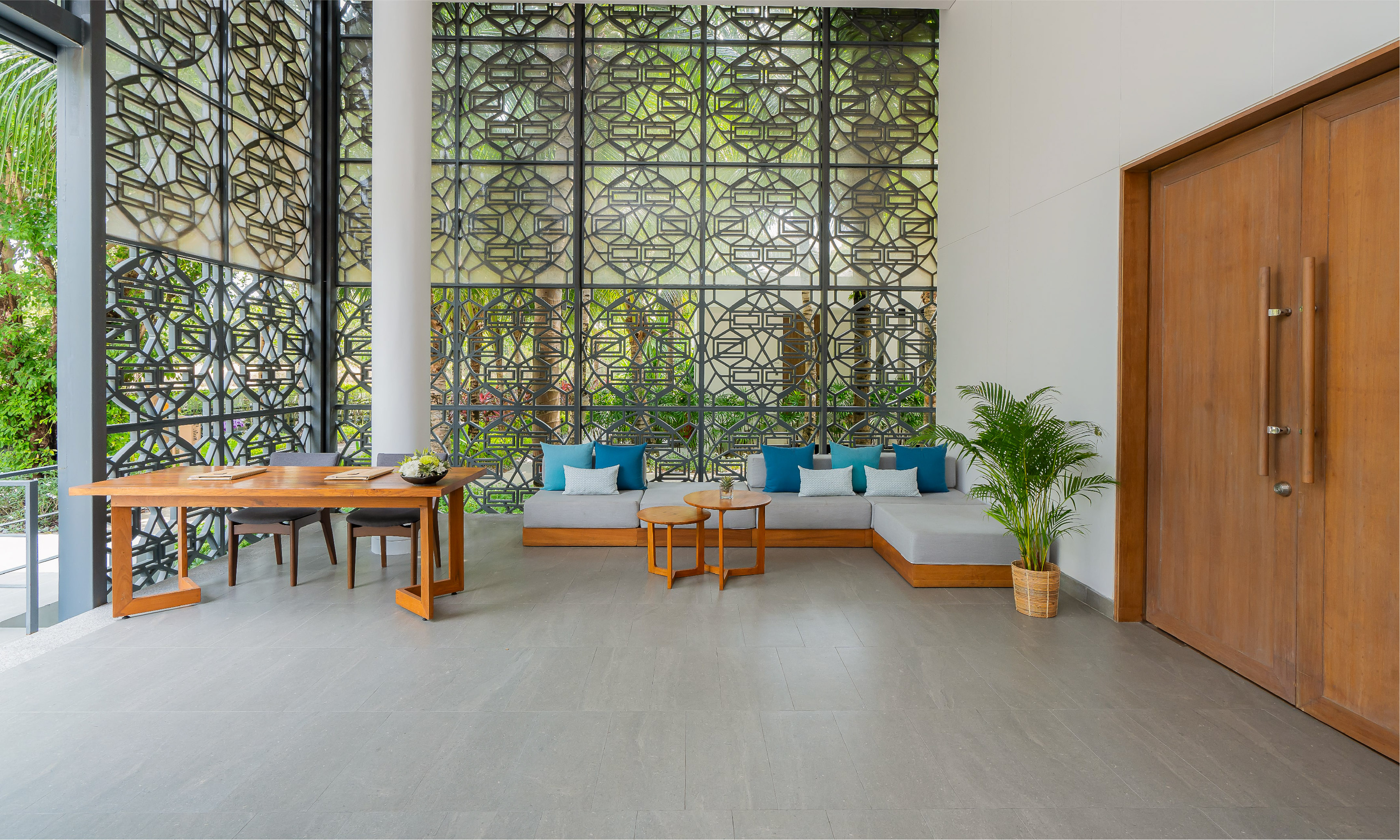 Modern hotel lobby with geometric screen, wooden reception desk & lounge.