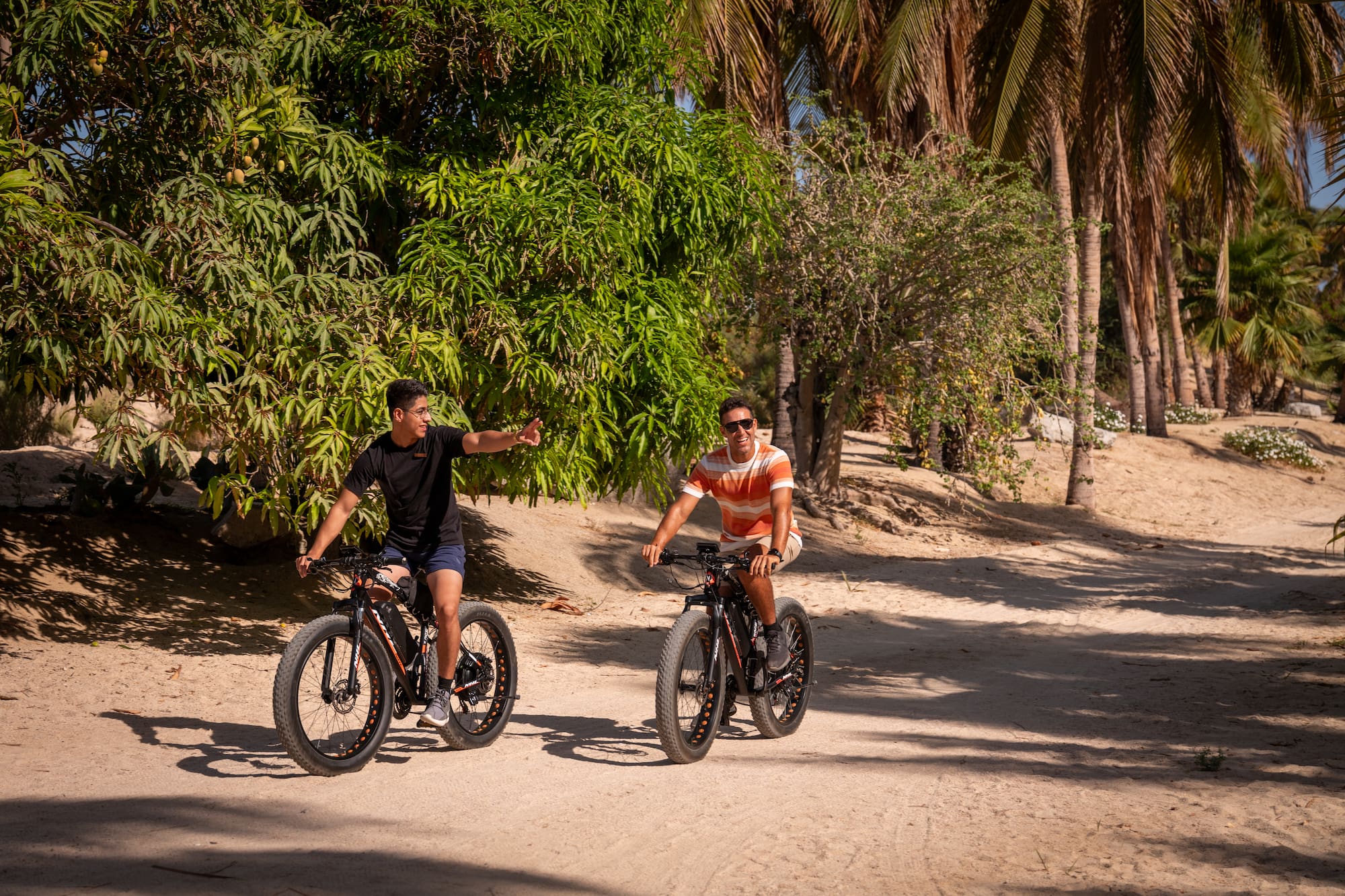 two men riding bikes on a dirt road