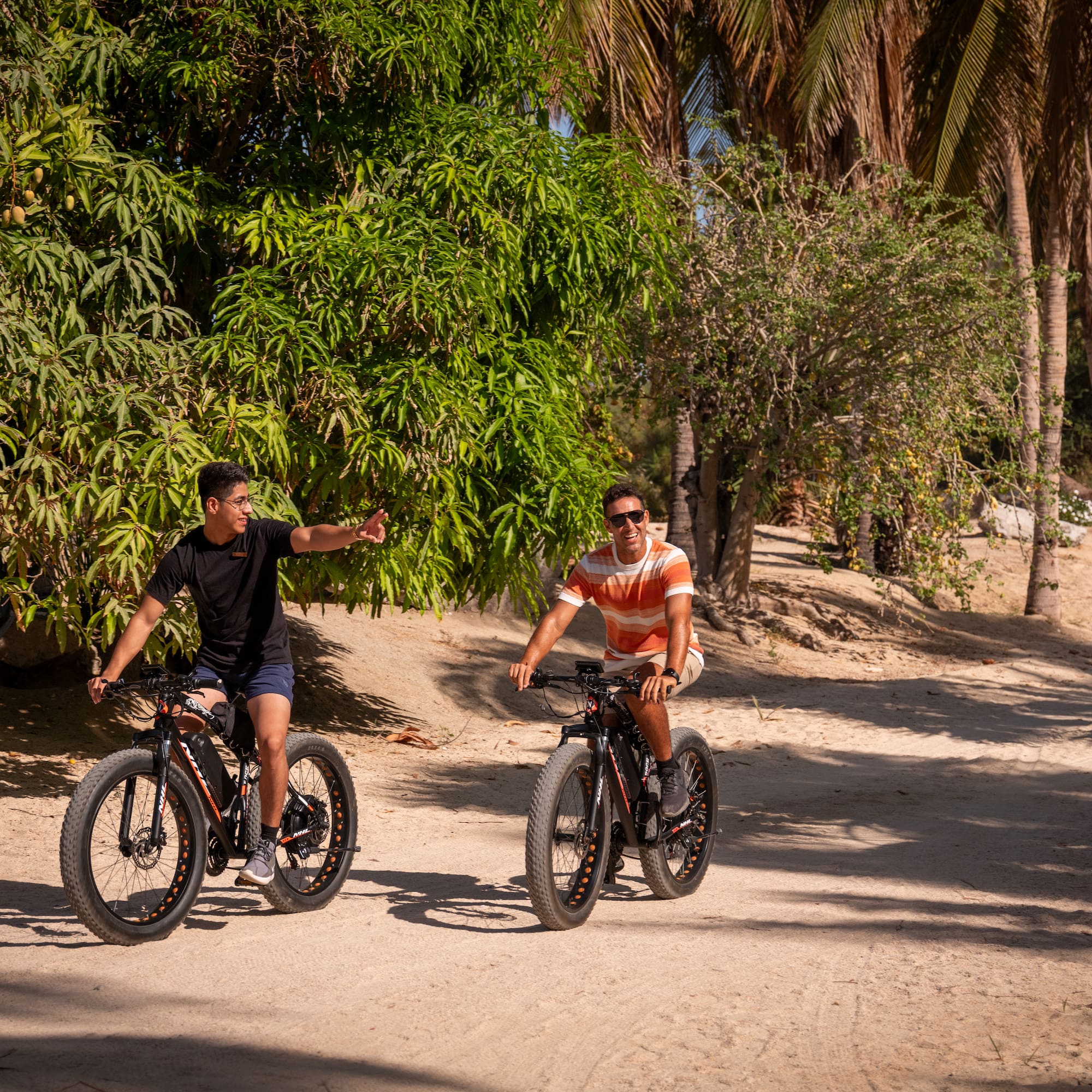 two men riding bikes on a dirt road