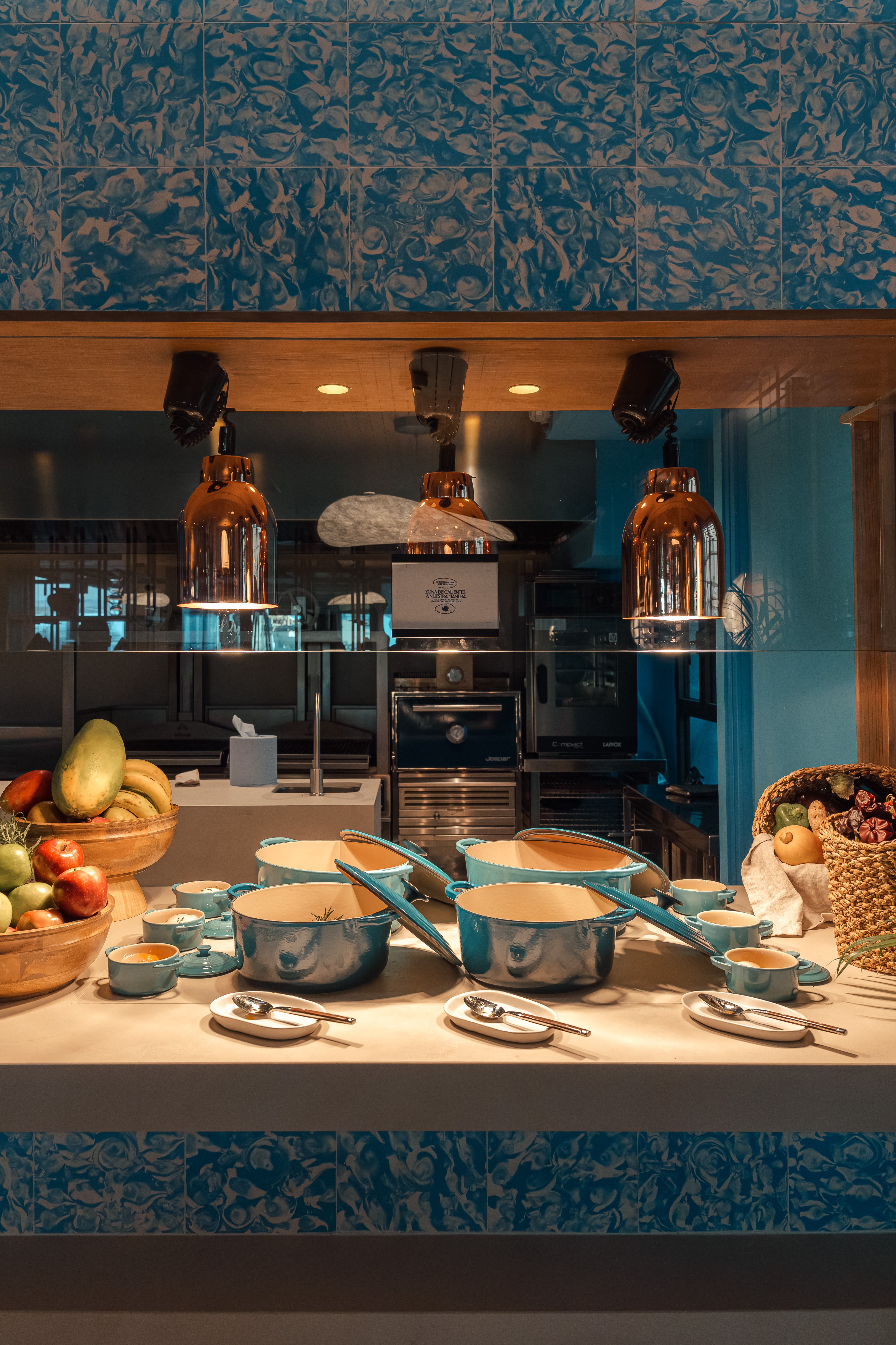 Buffet display with teal serving pots, fresh fruit, and a modern kitchen backdrop.