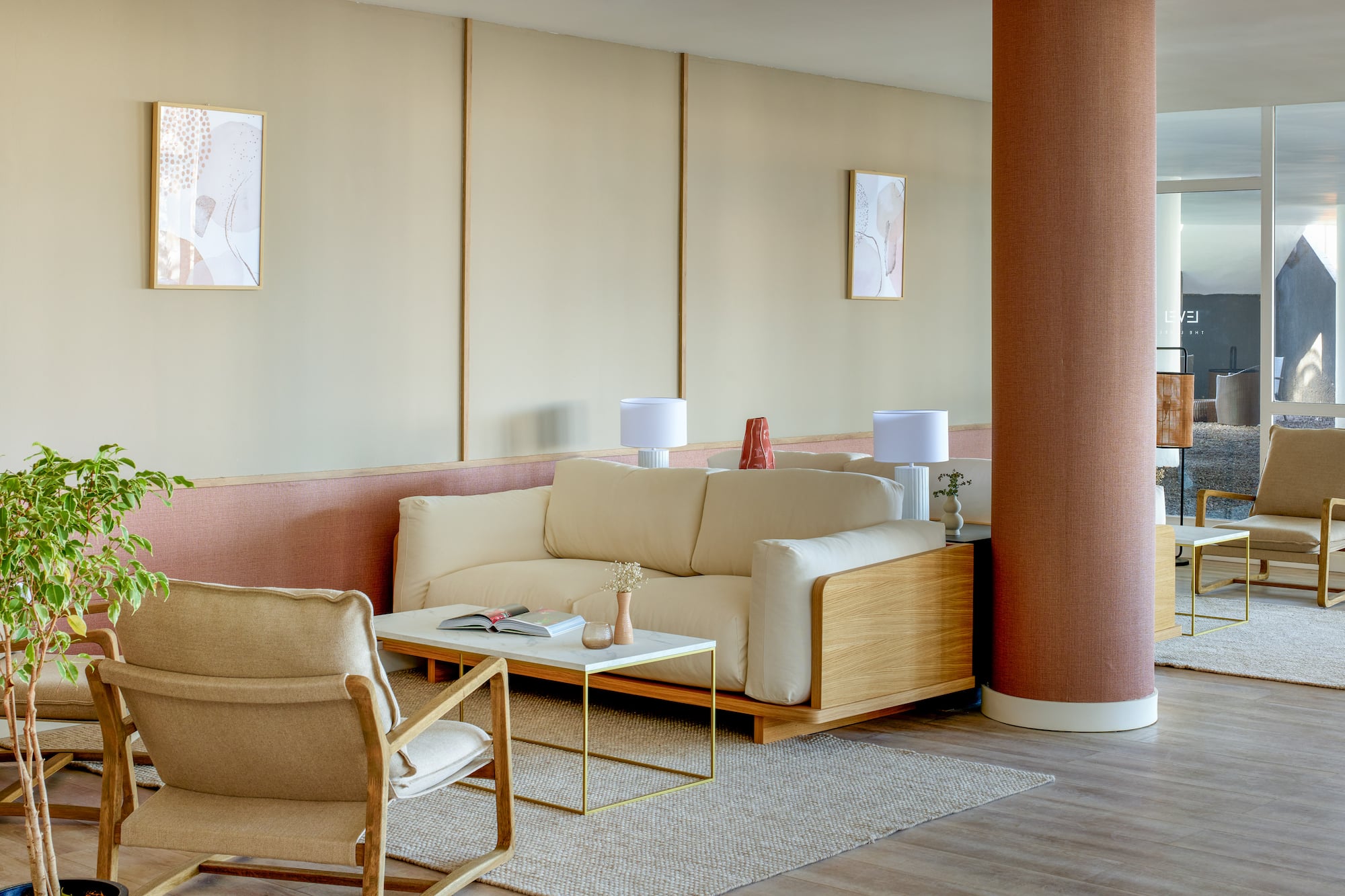 Modern lounge with cream sofa, wood chairs, marble coffee table, neutral decor.