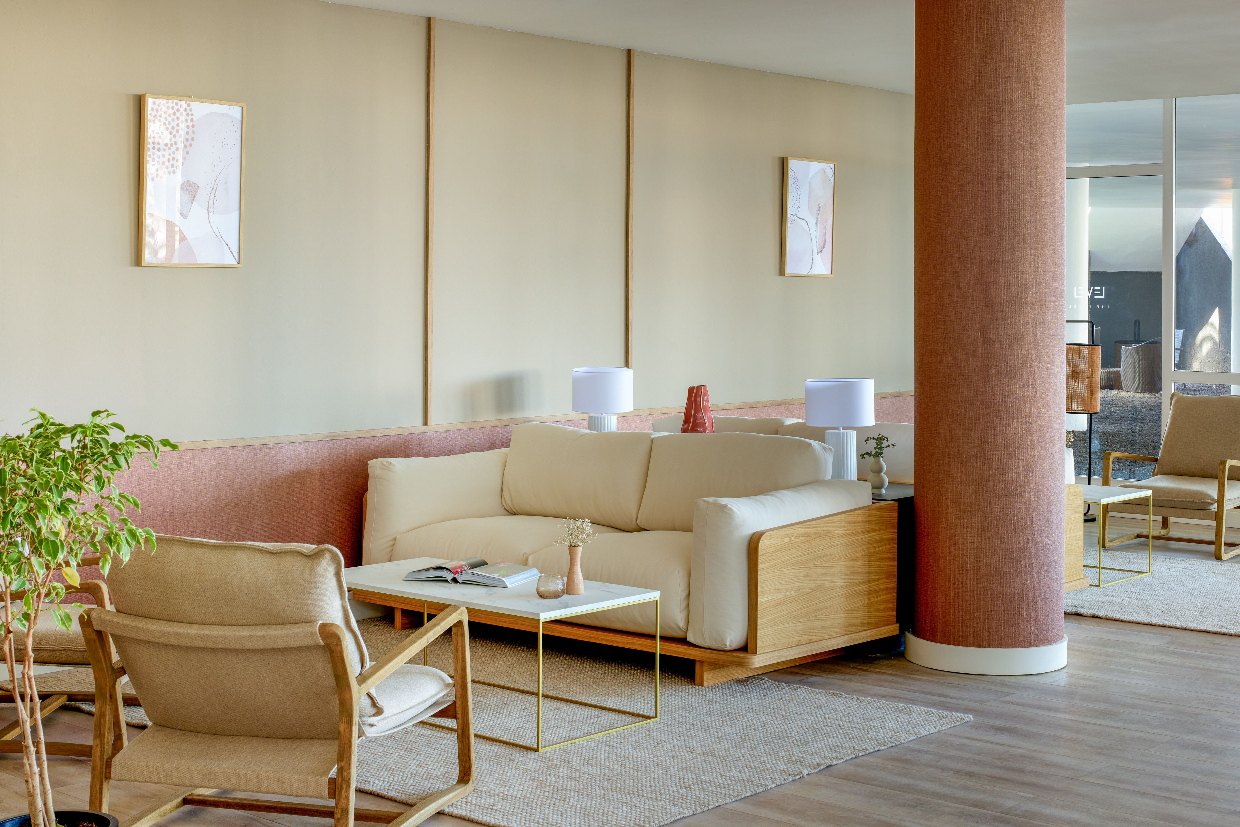 Modern lounge with cream sofa, wood chairs, marble coffee table, neutral decor.