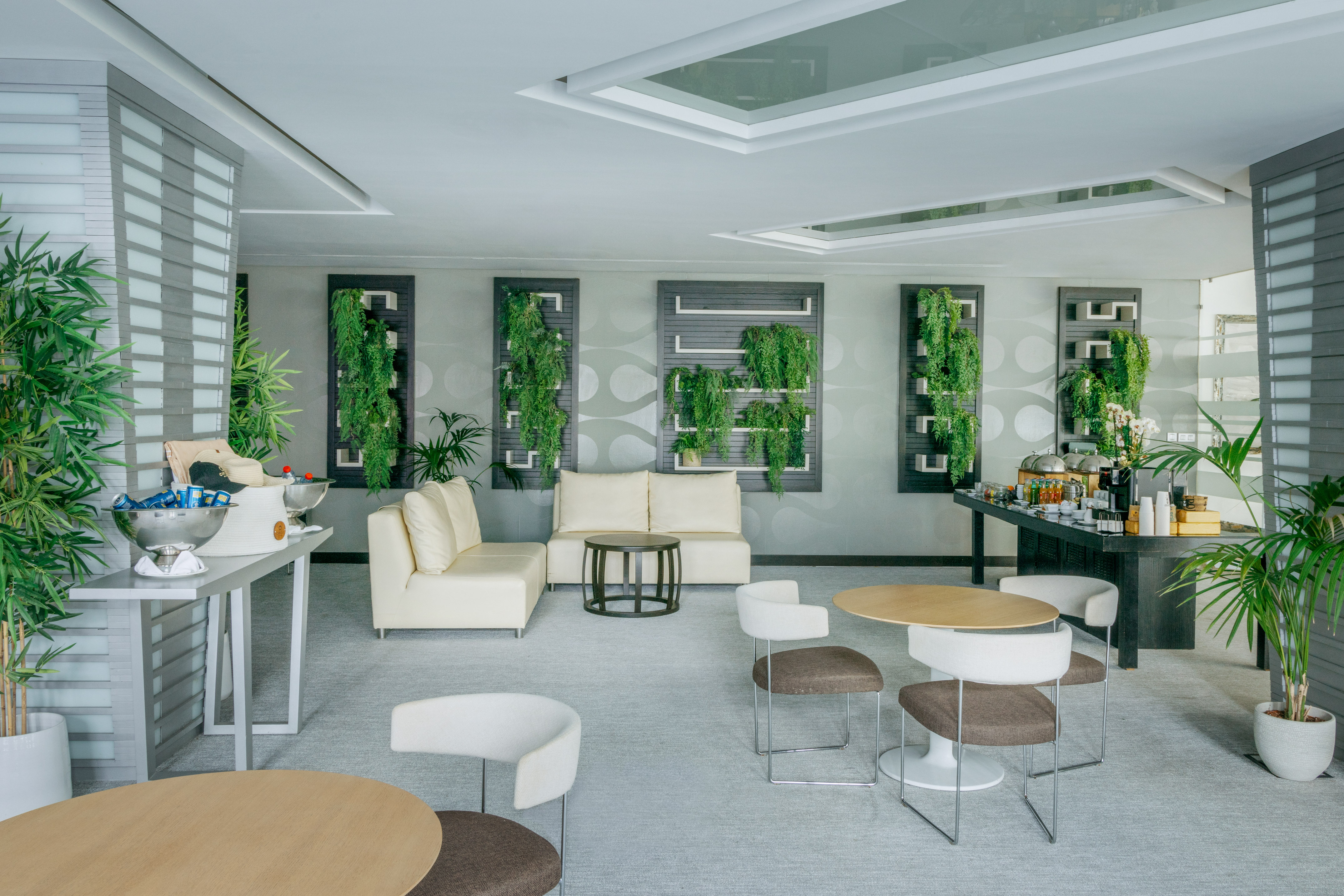 Modern lounge interior with vertical gardens, cream sofas, and refreshment station.