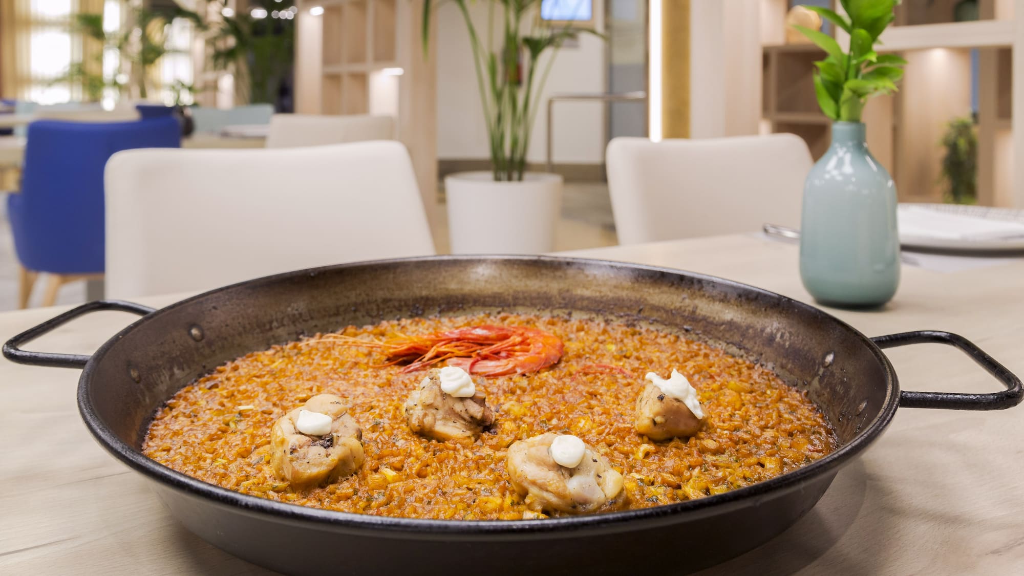 Traditional chicken and prawn paella in a pan on a restaurant table.