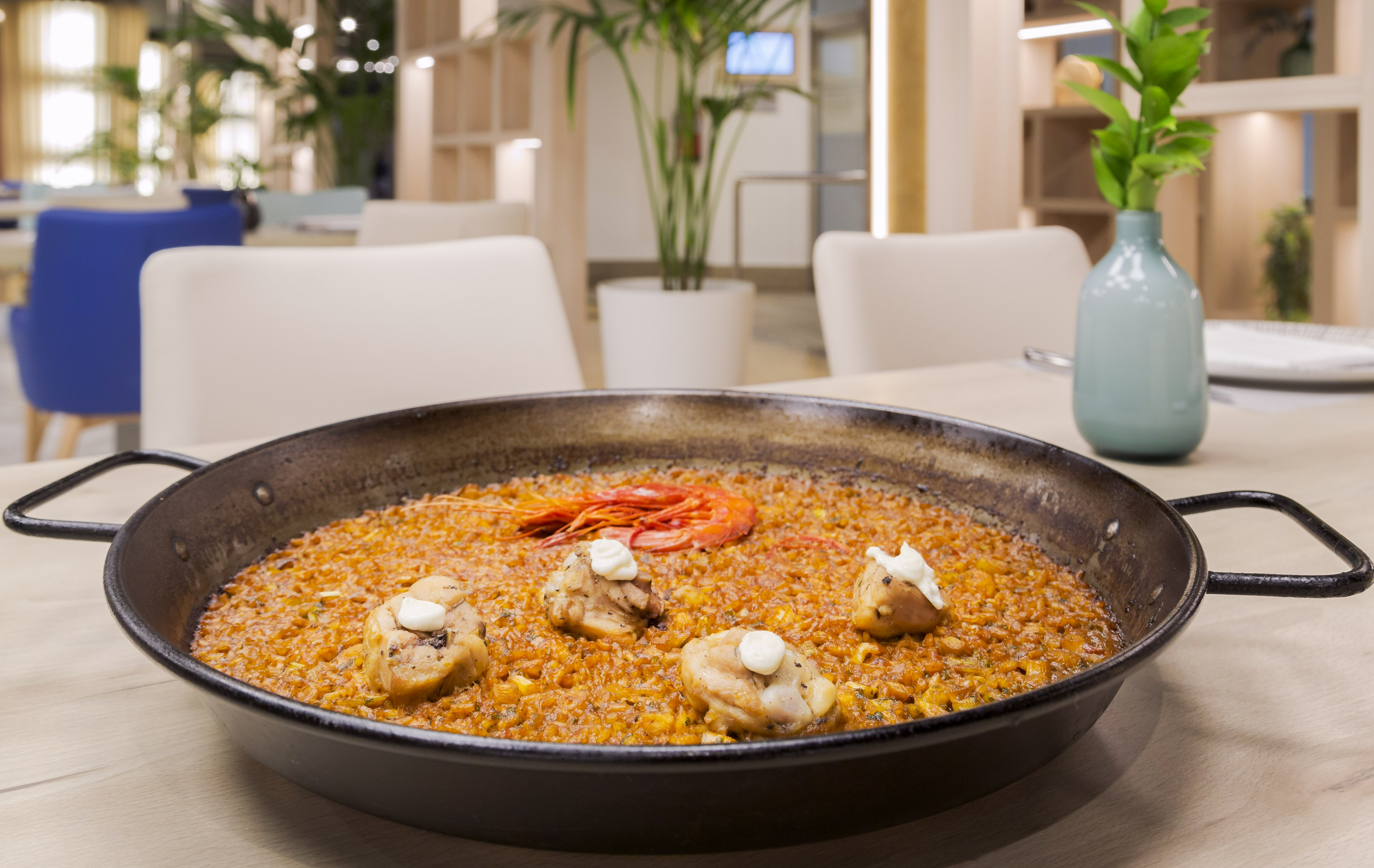 Traditional chicken and prawn paella in a pan on a restaurant table.