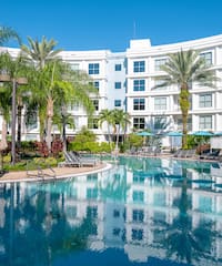 a pool with palm trees and a building in the background
