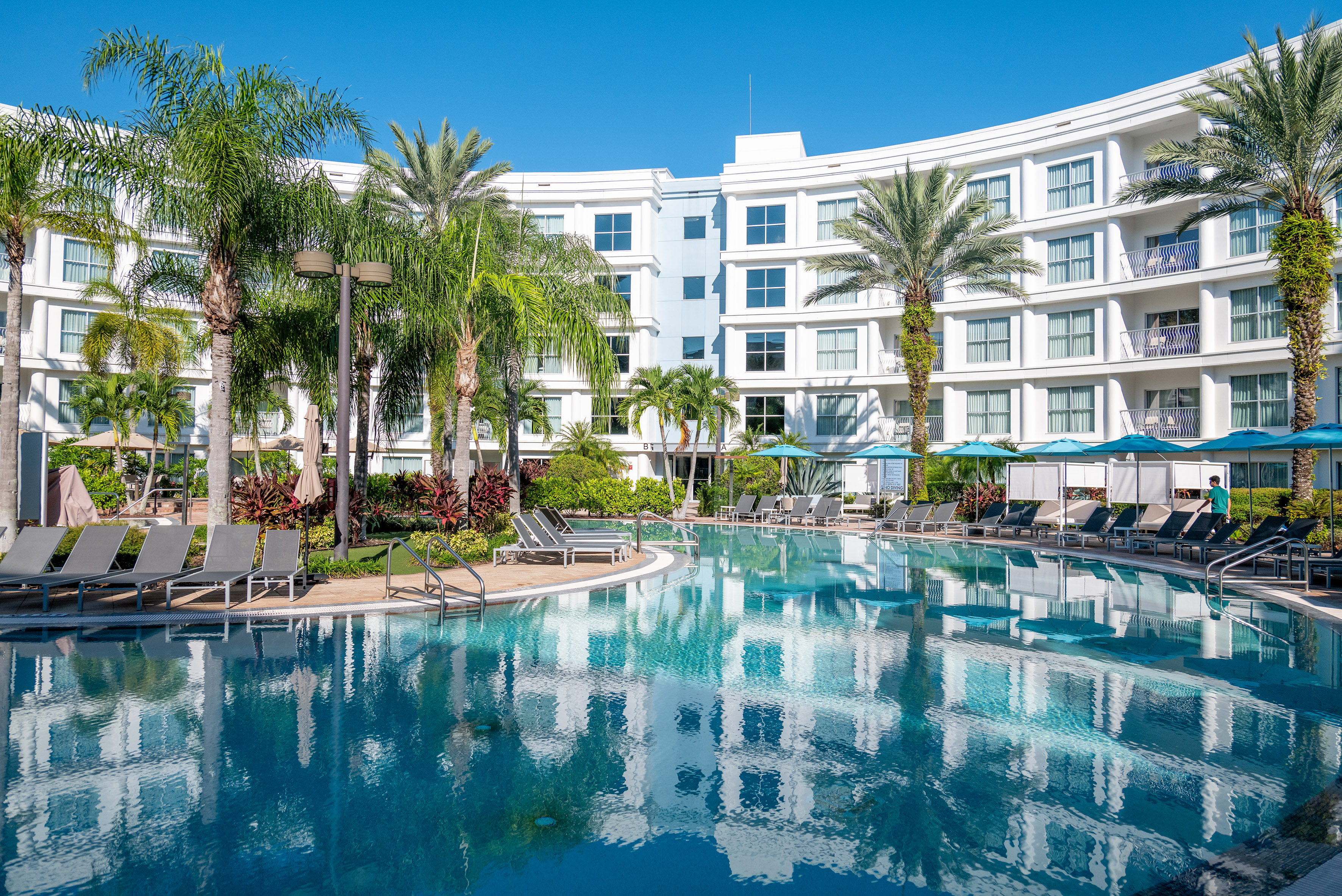 a pool with palm trees and a building in the background