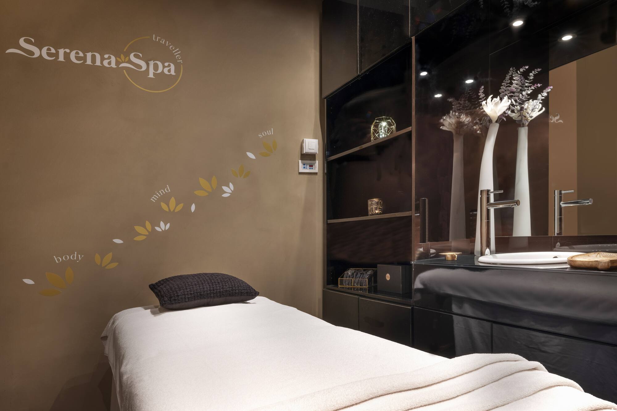 Serena Spa massage room with treatment bed, modern dark vanity, and elegant decor.