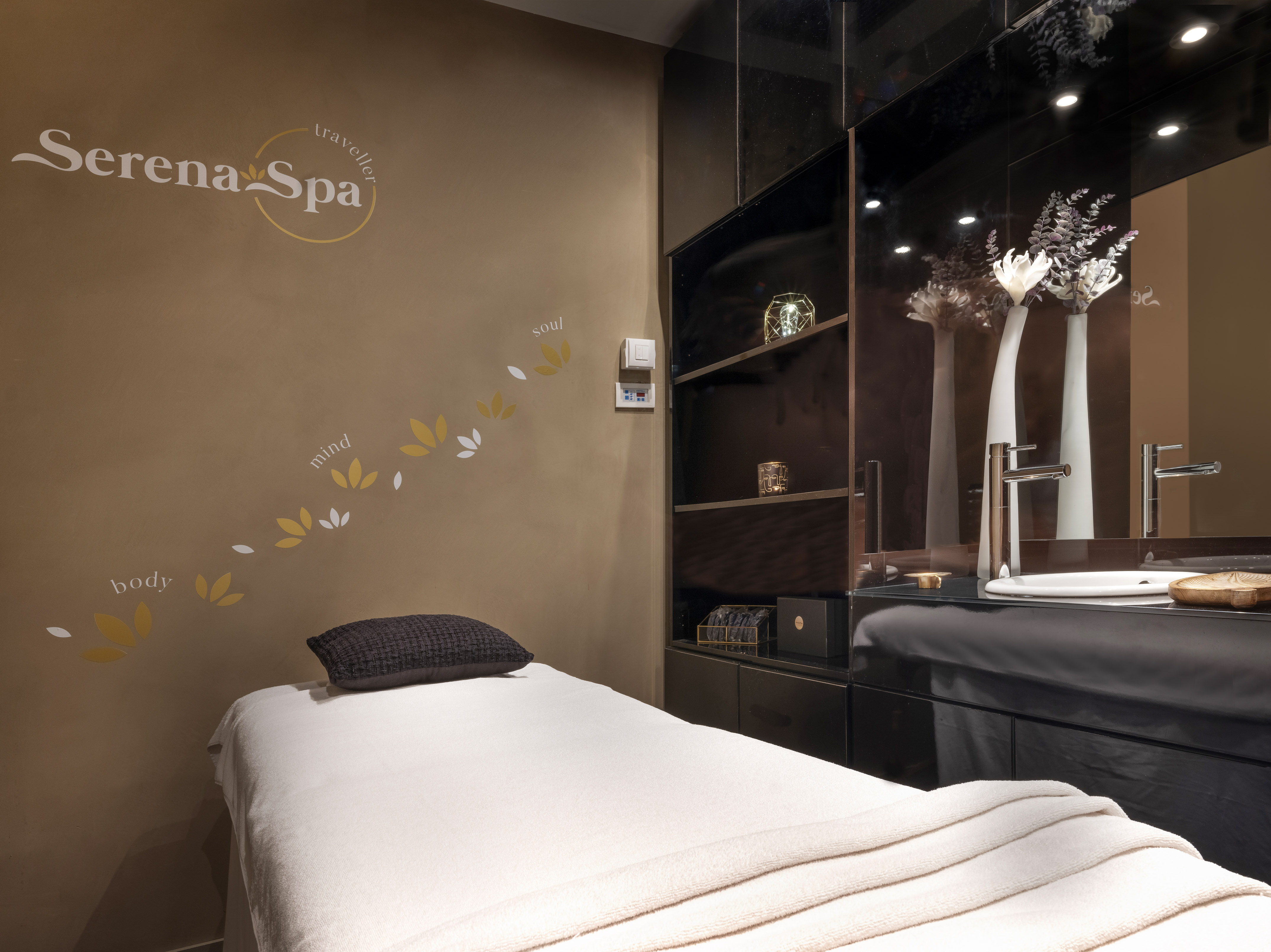 Serena Spa massage room with treatment bed, modern dark vanity, and elegant decor.