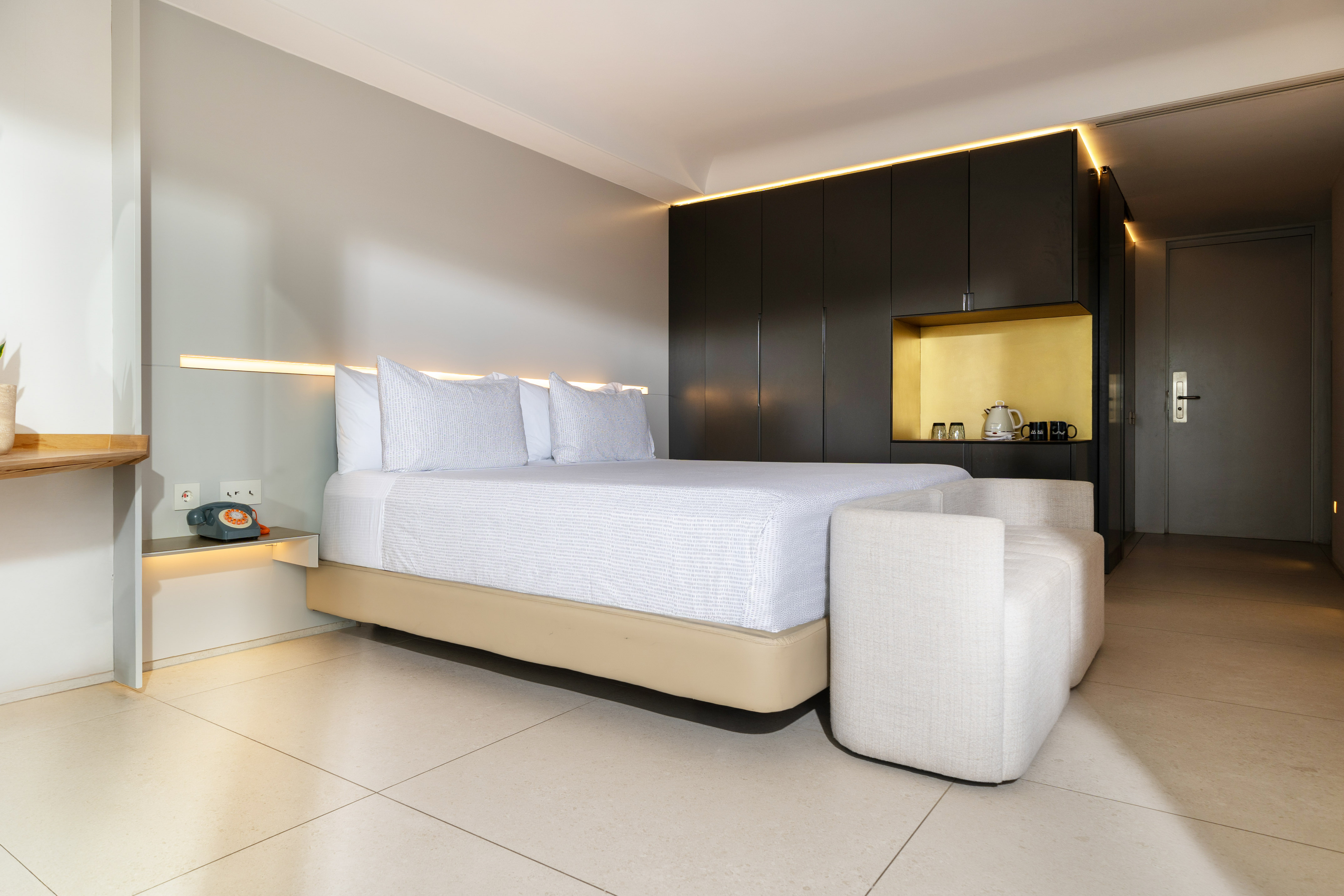 Modern hotel bedroom with king bed, dark cabinets, and subtle lighting.