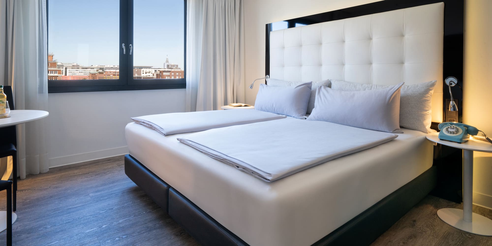 a bed with white sheets and pillows in a room with a window