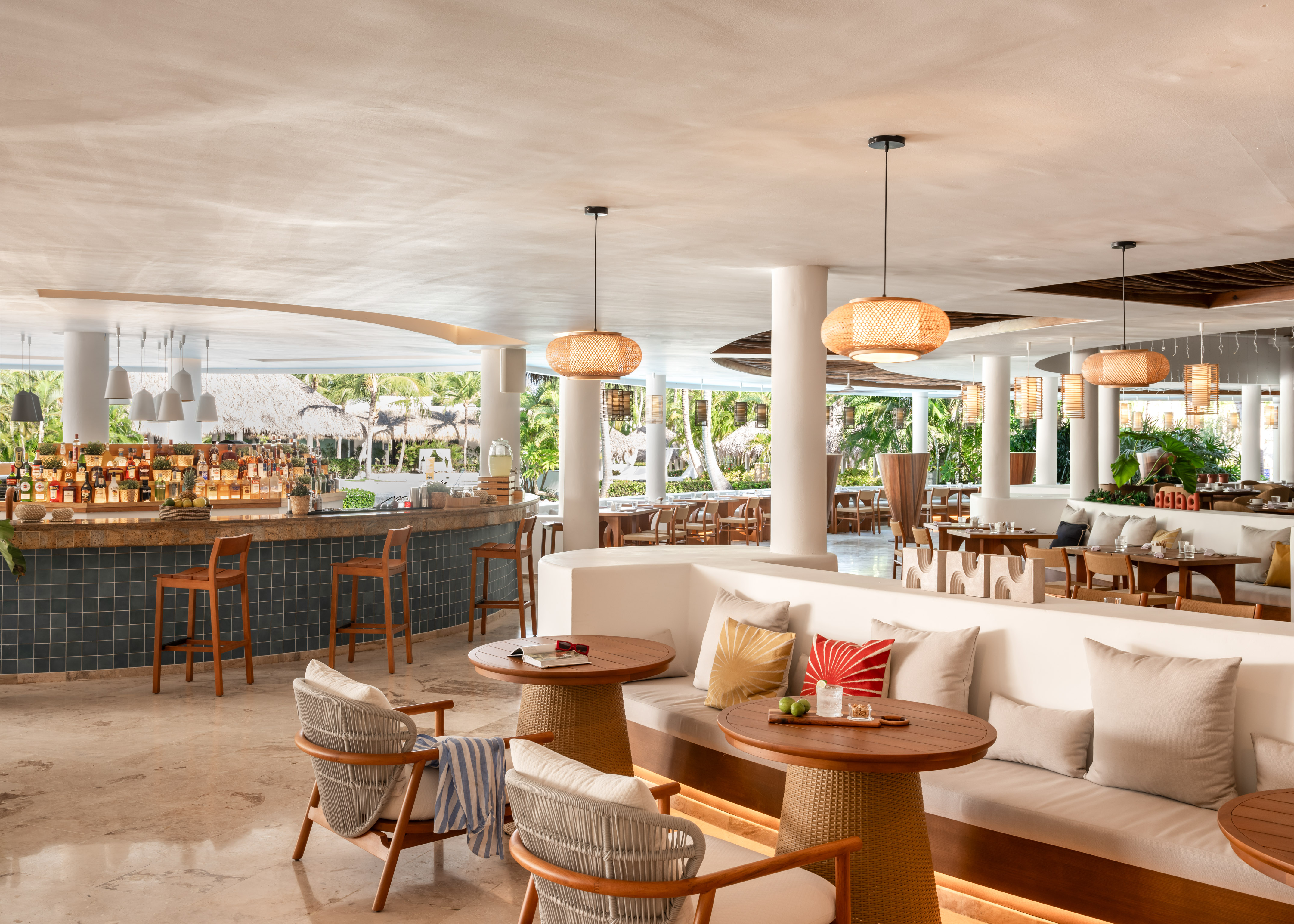 Modern tropical resort restaurant with bar, lounge seating, and outdoor views.