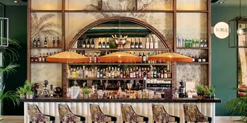 a bar with a row of chairs and bottles