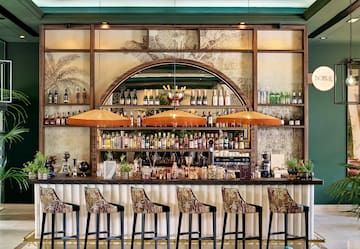 a bar with a row of chairs and bottles