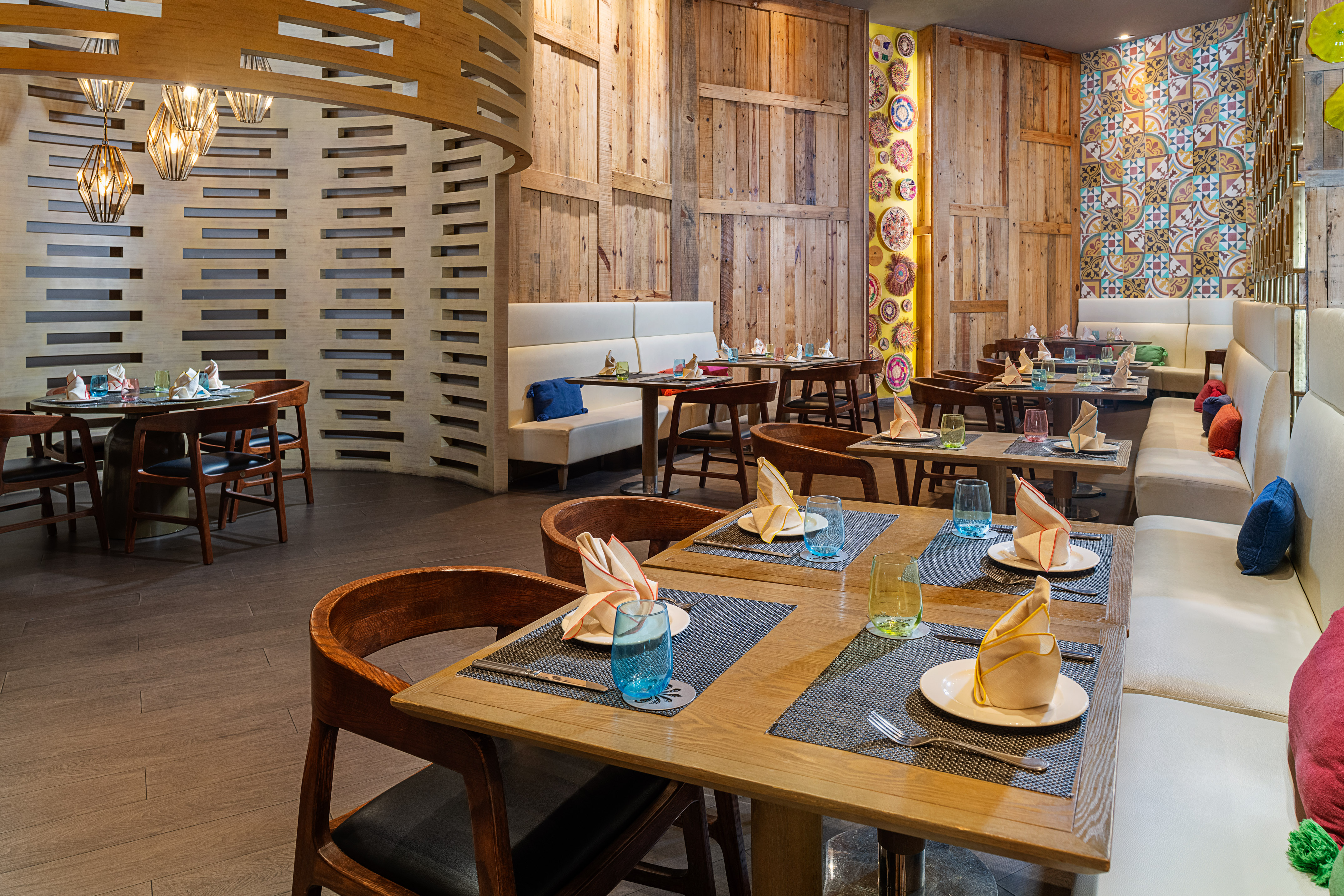Modern restaurant dining room with wooden walls, set tables, and banquette seating.