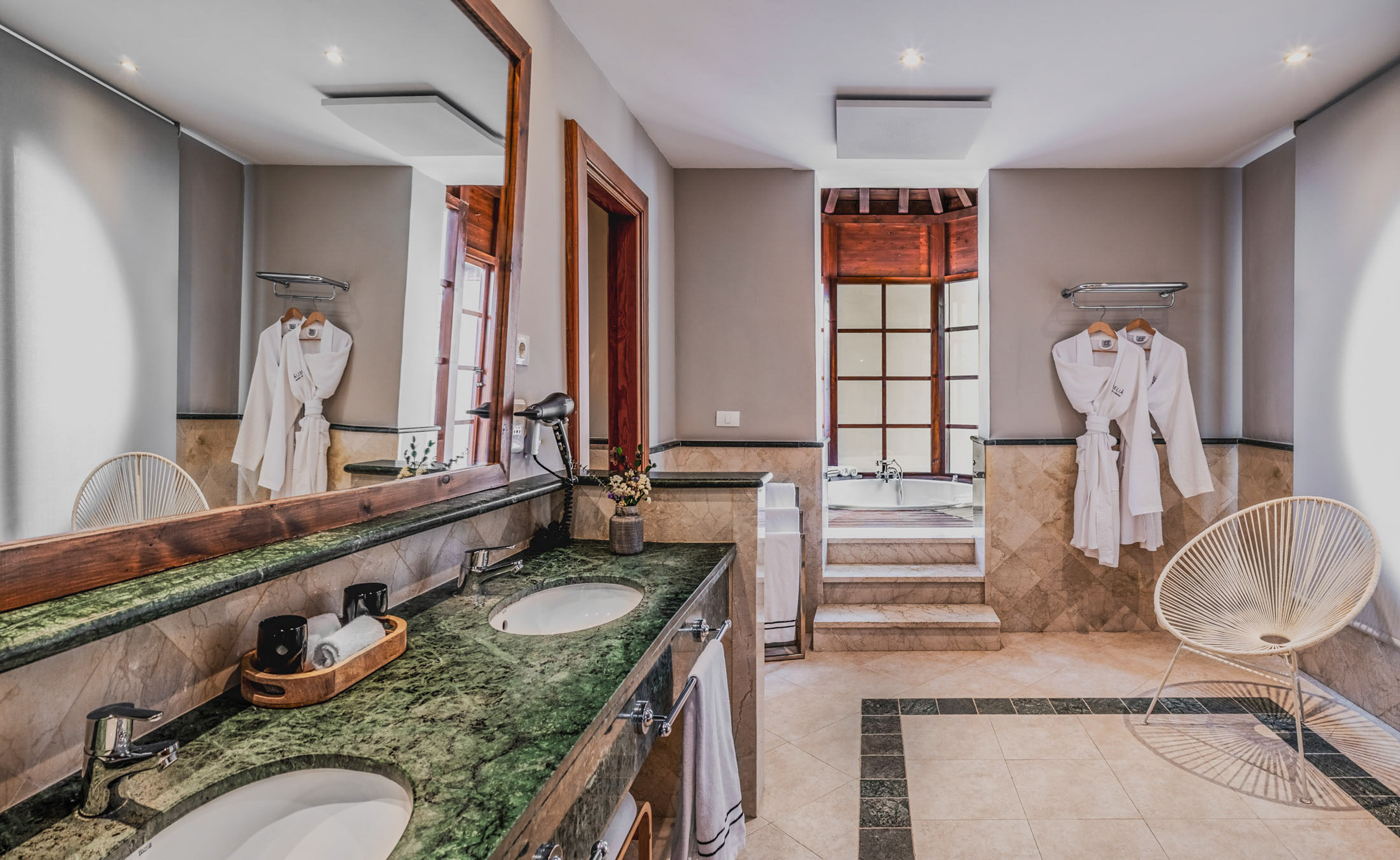 Spacious bathroom: green marble double vanity, large mirror, elevated bathtub.