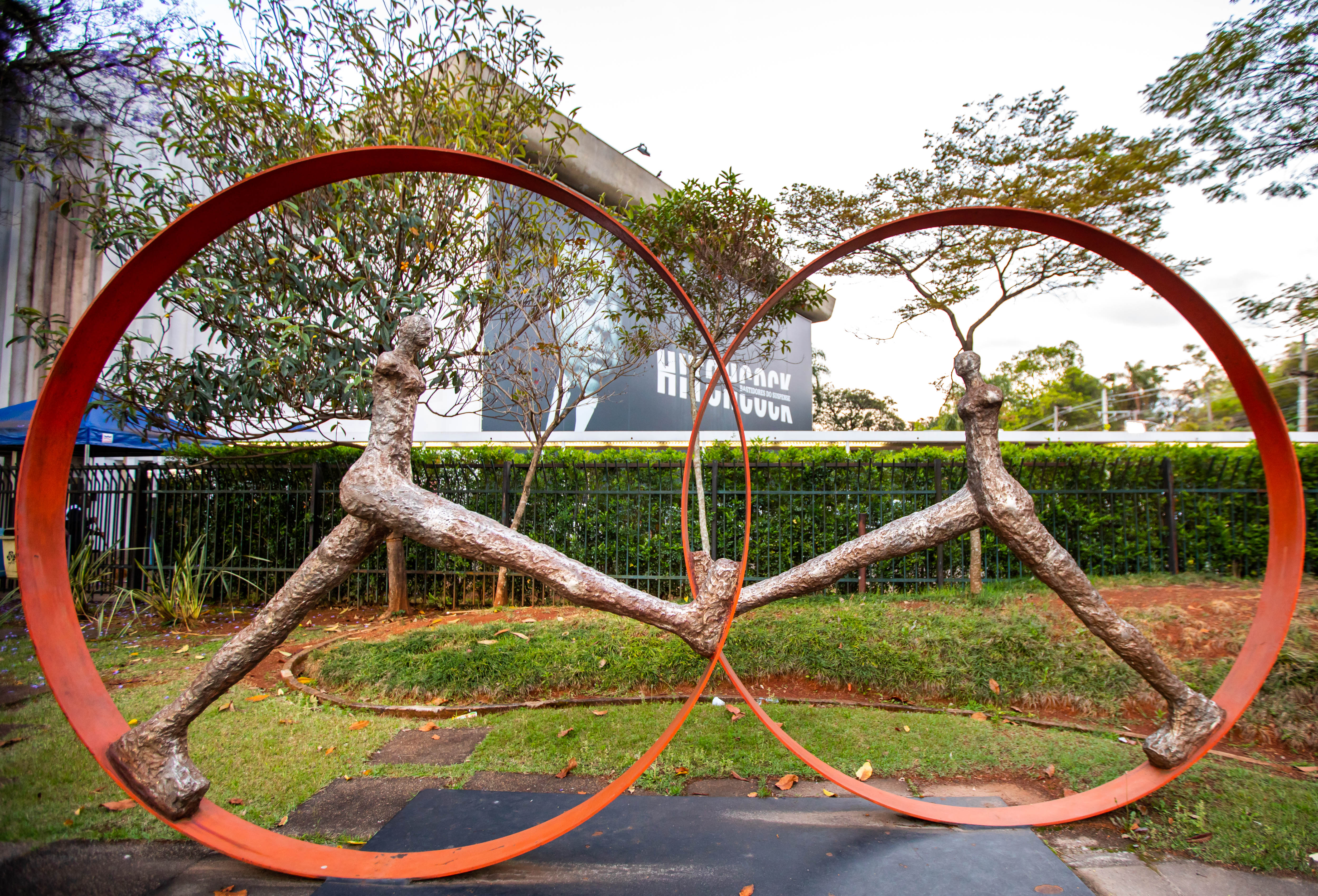 Abstract outdoor metal sculpture: intertwined orange rings and textured forms.