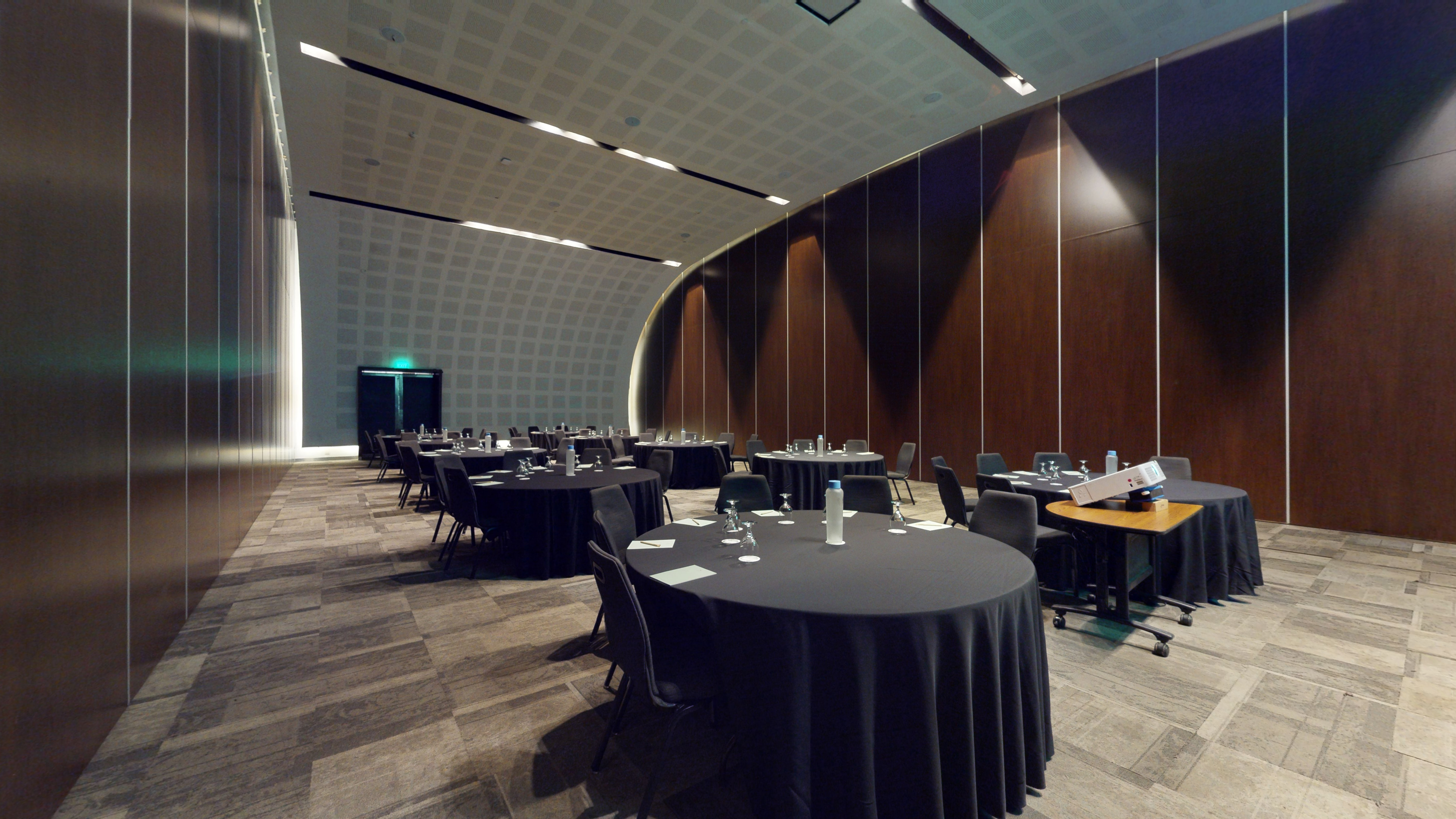 Modern conference room with black round tables, chairs, and curved walls.