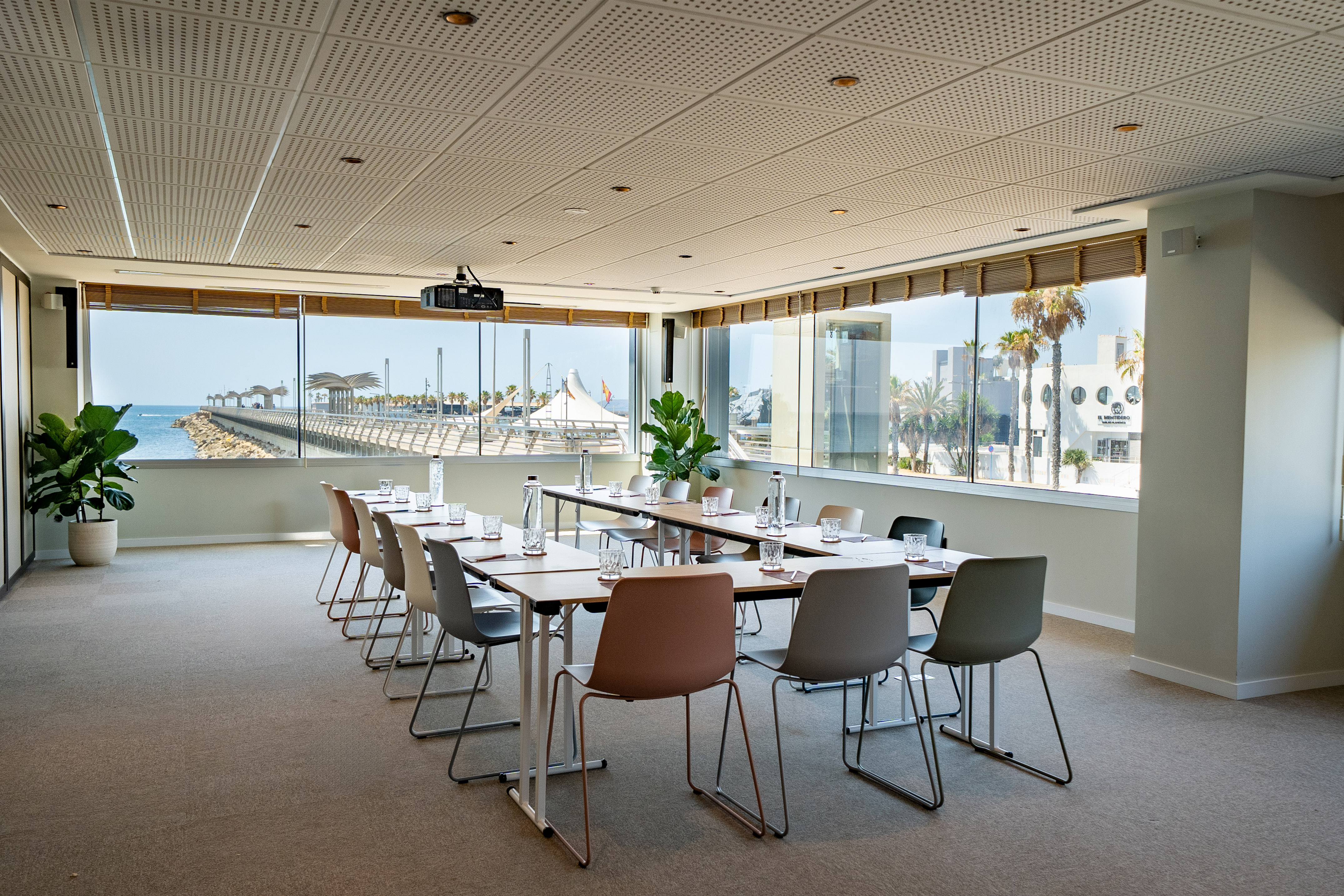 Oceanfront conference room with pier view, U-shaped tables, and projector.