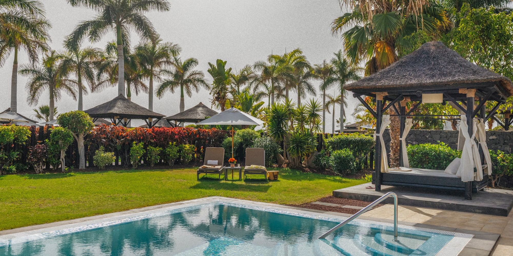 Tropical private pool, palm trees, sun loungers, and thatched cabana.