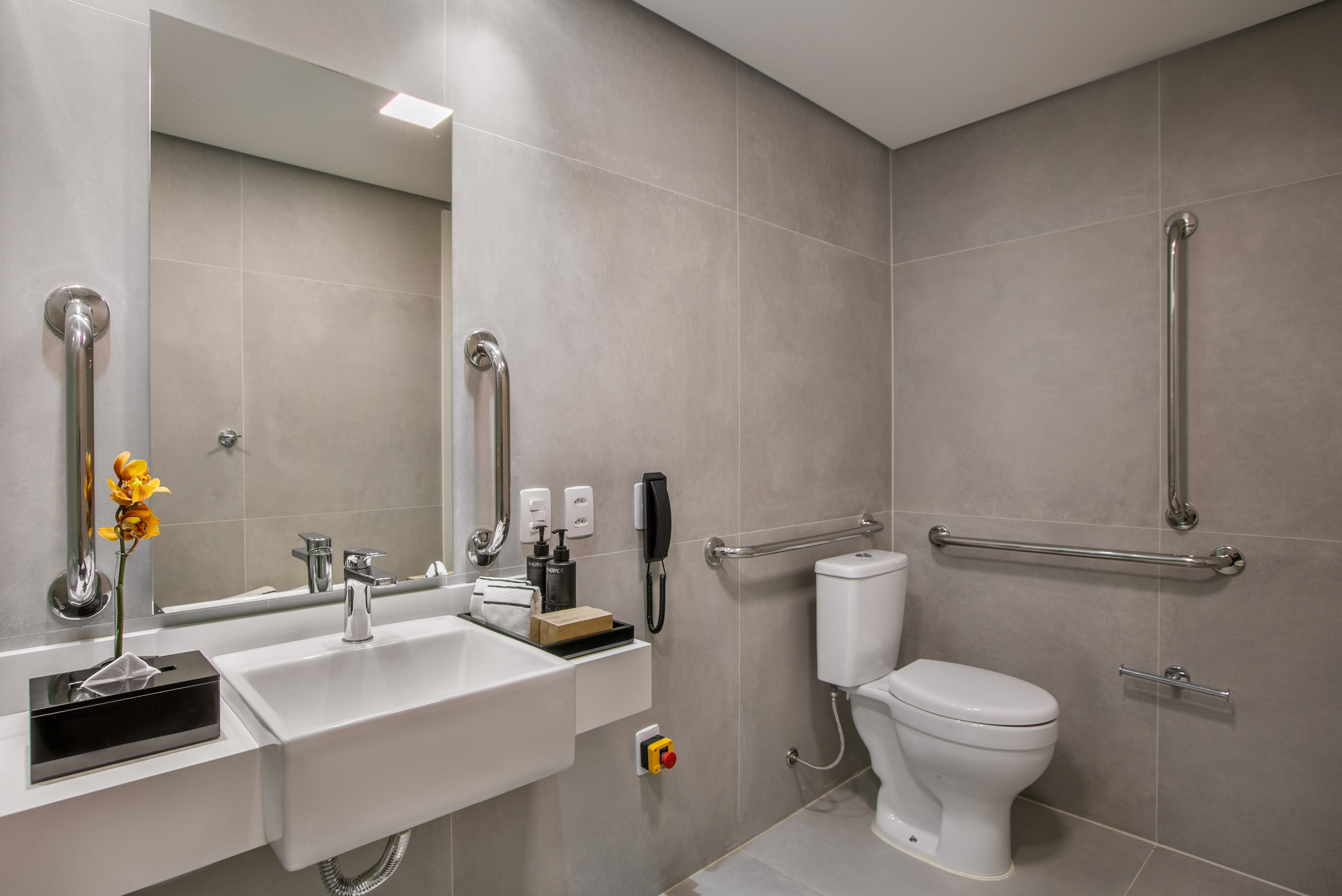 ADA compliant bathroom with grab bars, toilet, sink, and emergency alert.