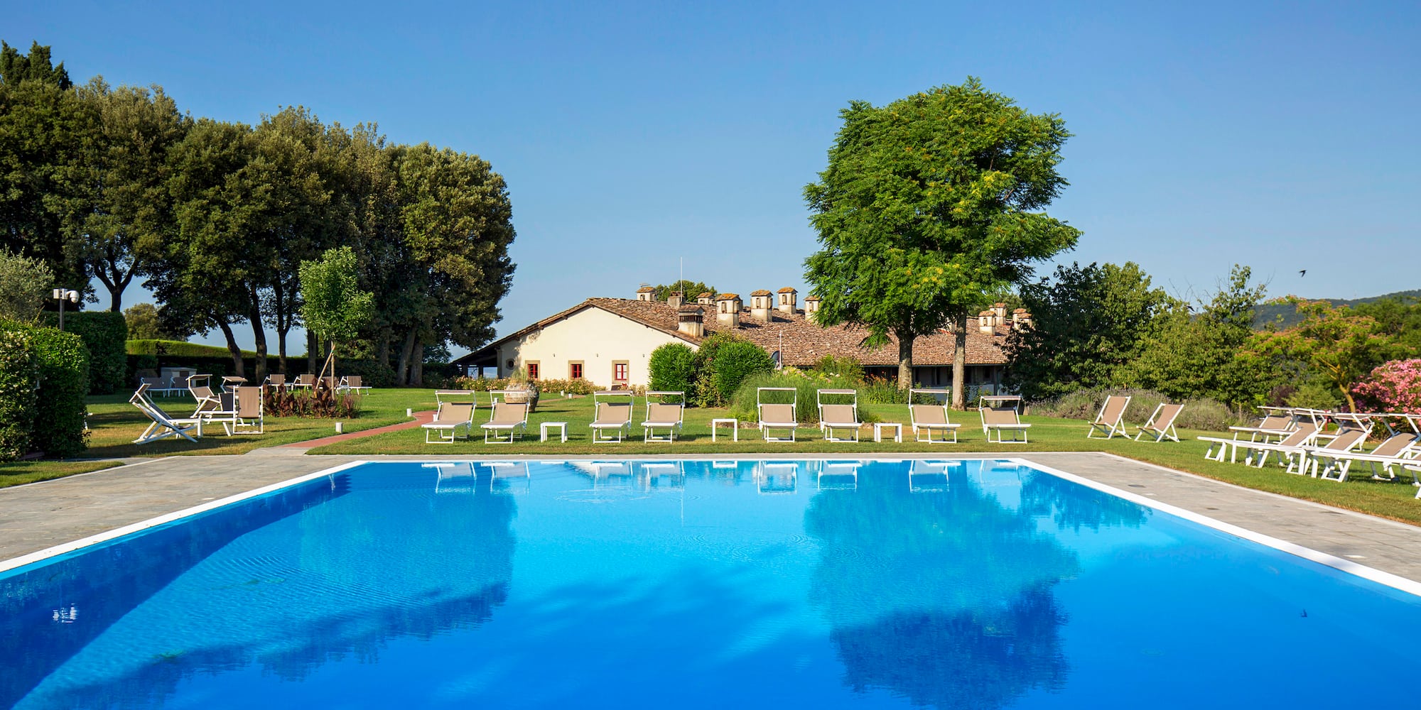 a pool with chairs and trees in the background