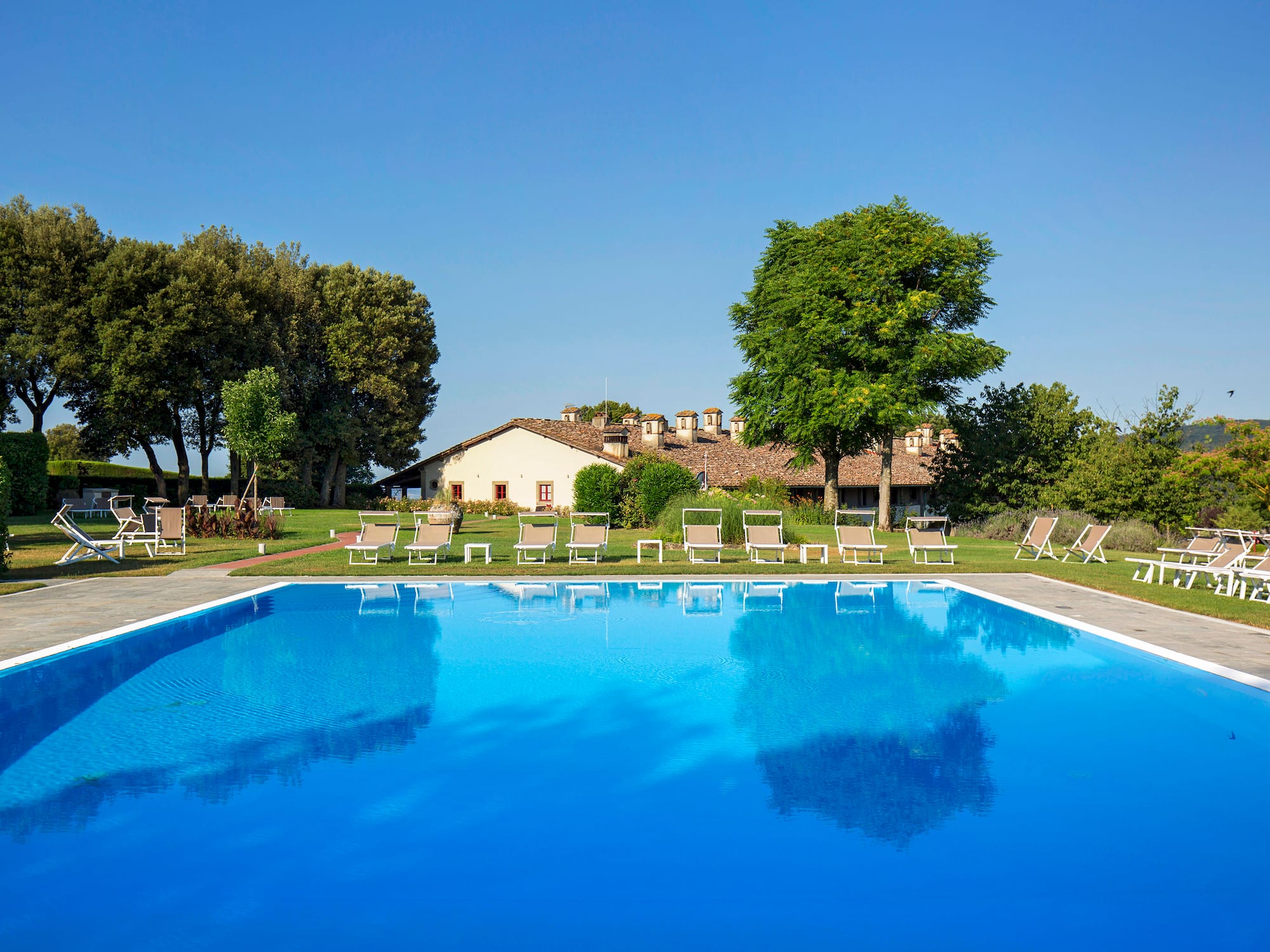a pool with chairs and trees in the background