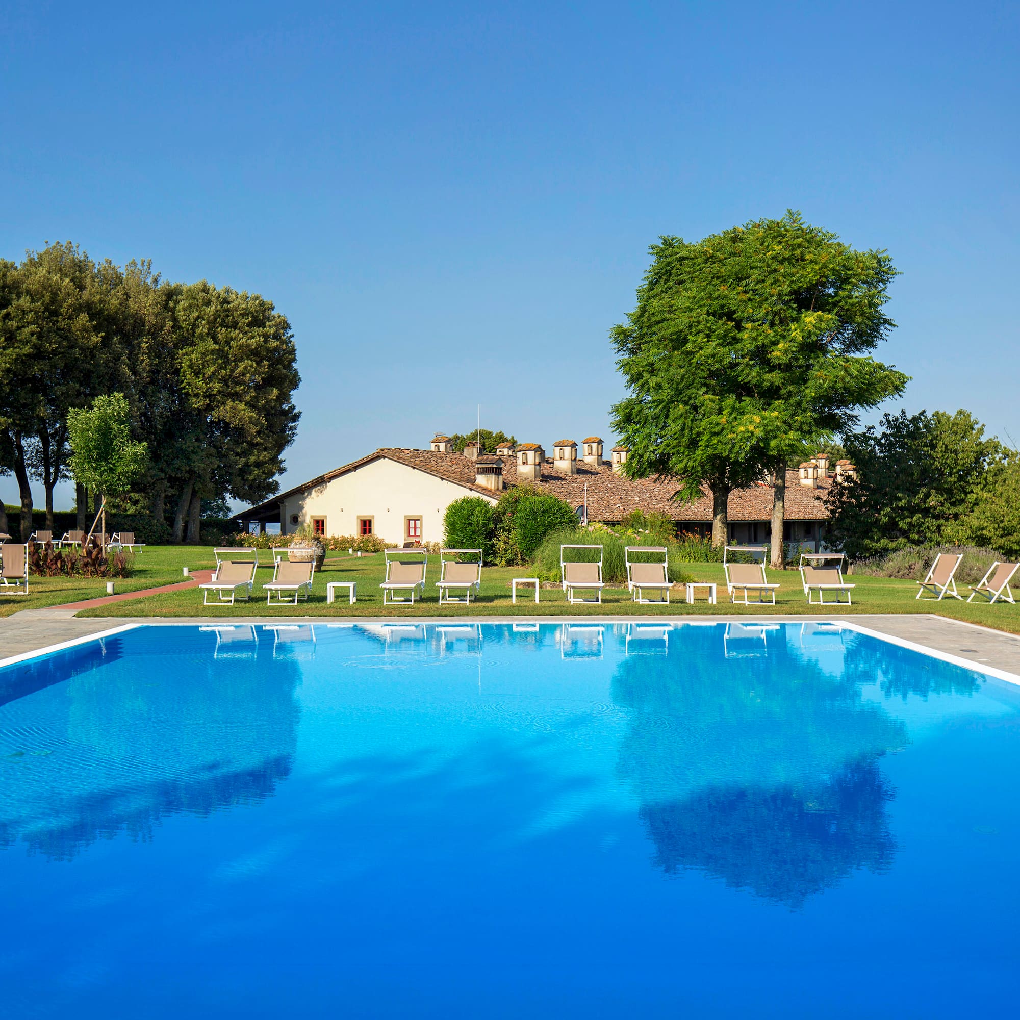 a pool with chairs and trees in the background