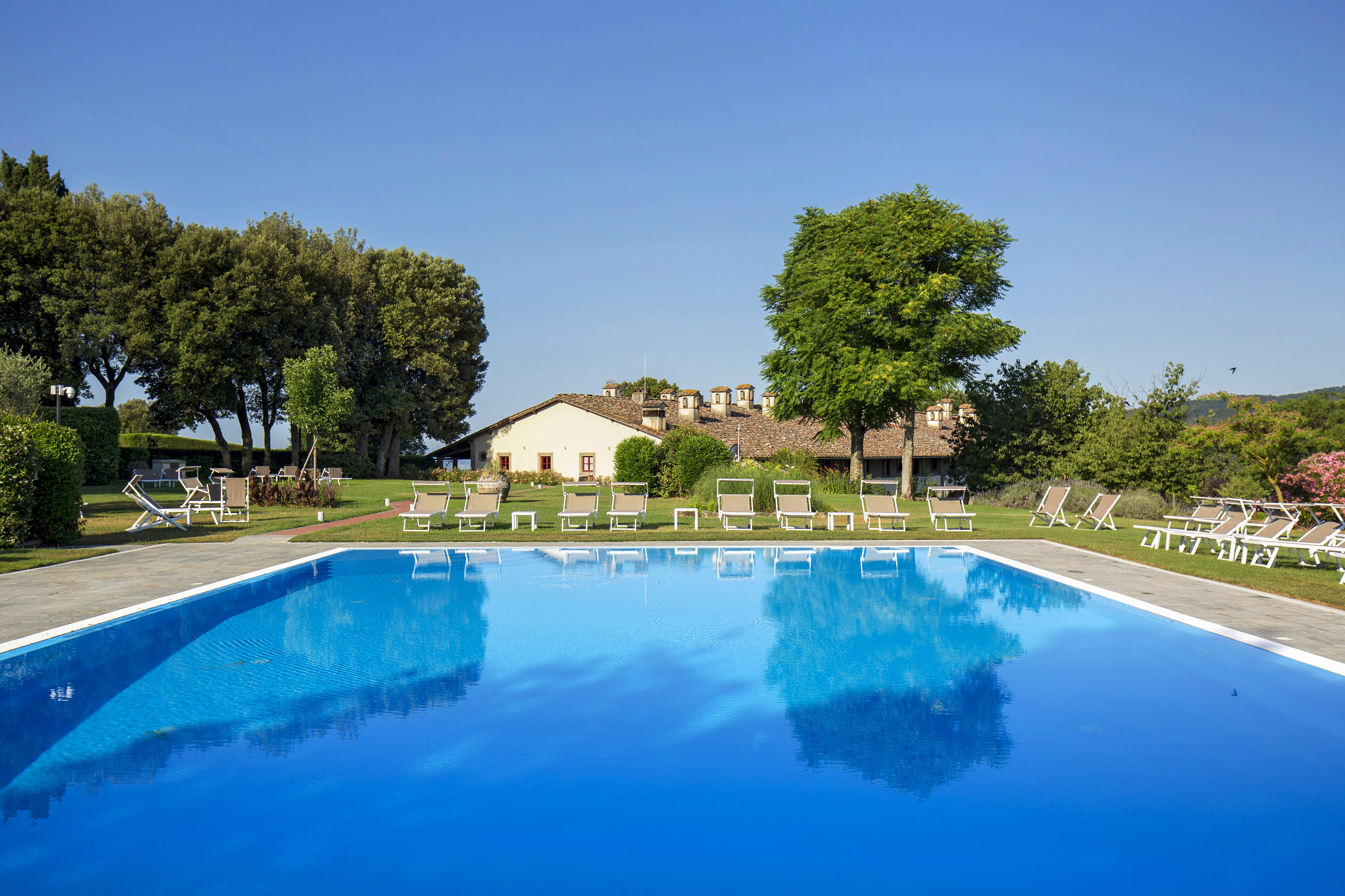 a pool with chairs and trees in the background