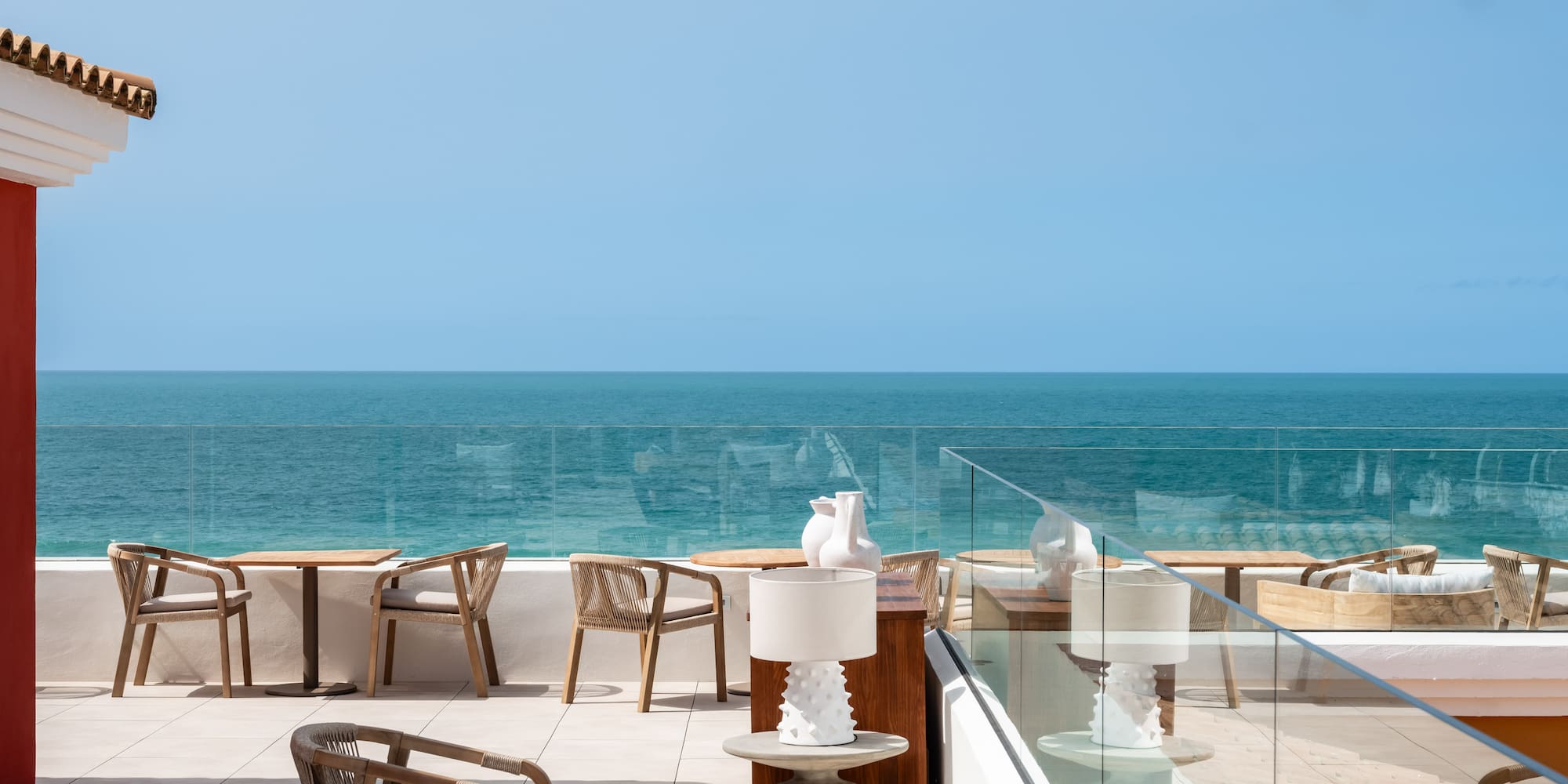 a patio with chairs and tables overlooking the ocean