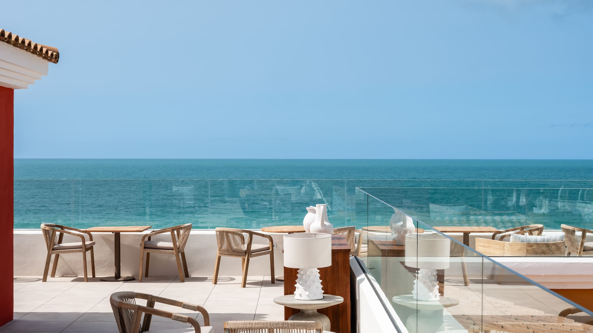a patio with chairs and tables overlooking the ocean