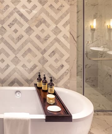 a bathtub with candles and soap on a tray