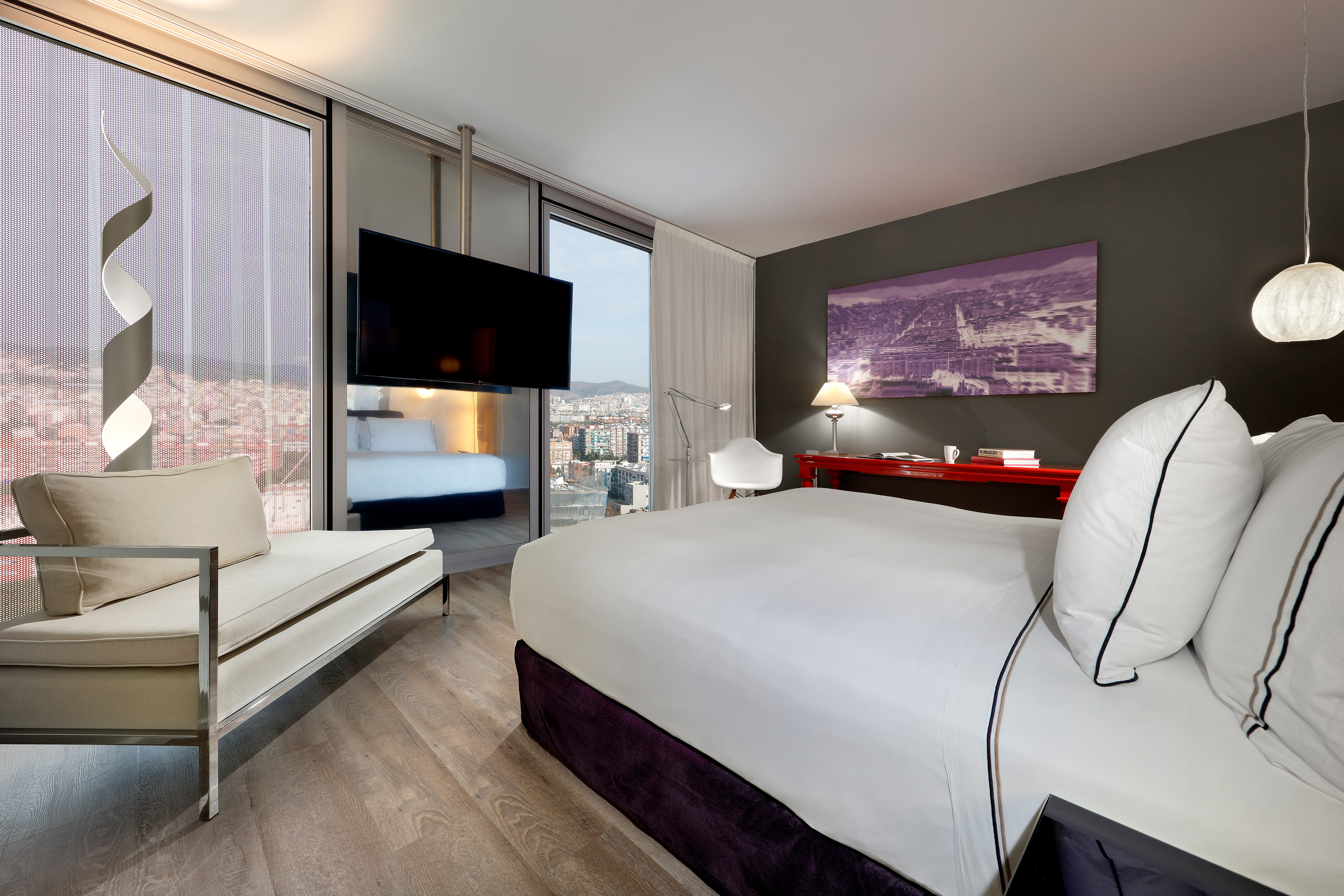Luxury hotel bedroom with city view, large bed, modern decor, and TV.
