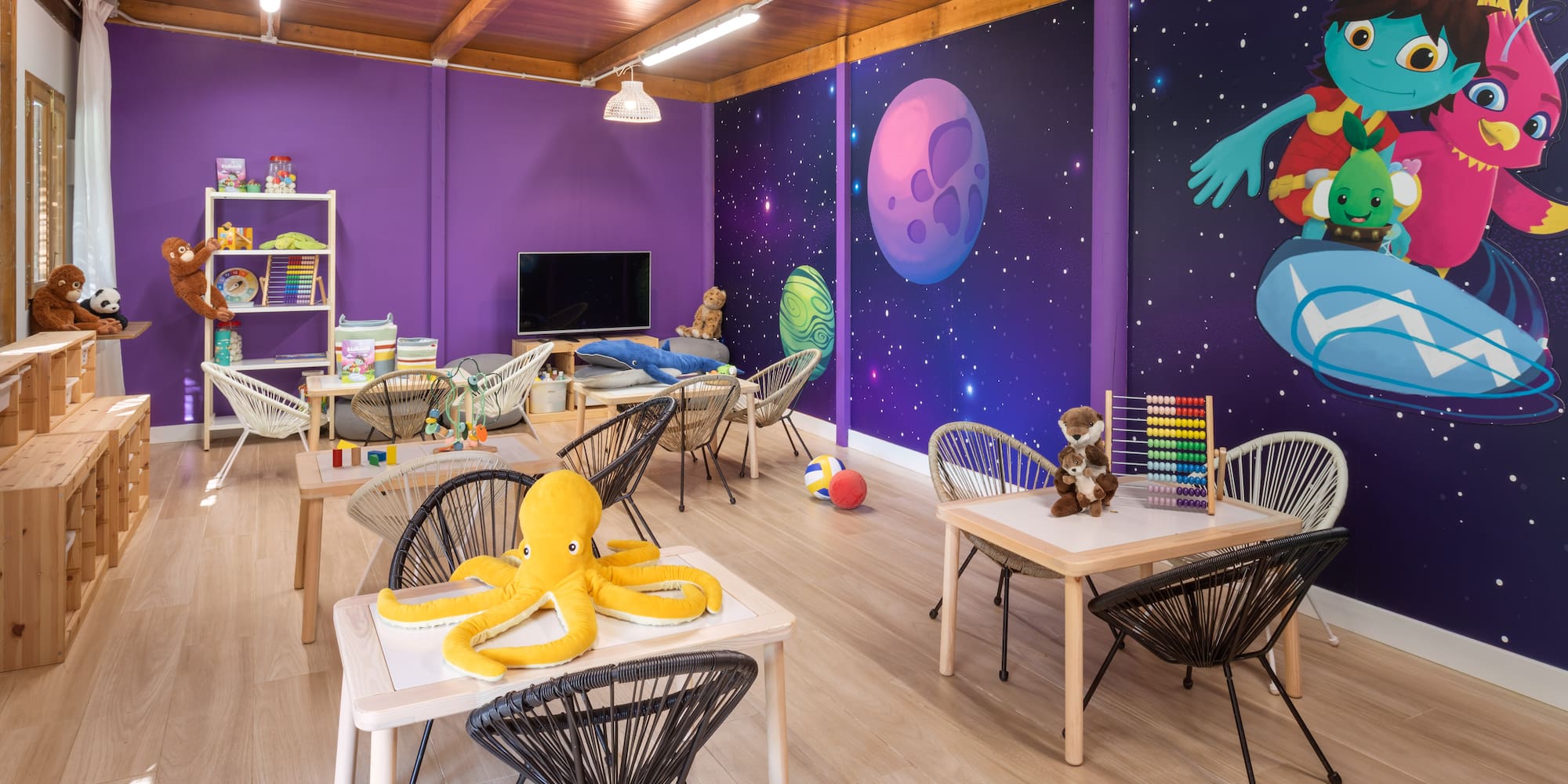 Bright, space-themed kids' playroom with small tables, chairs, and engaging toys.