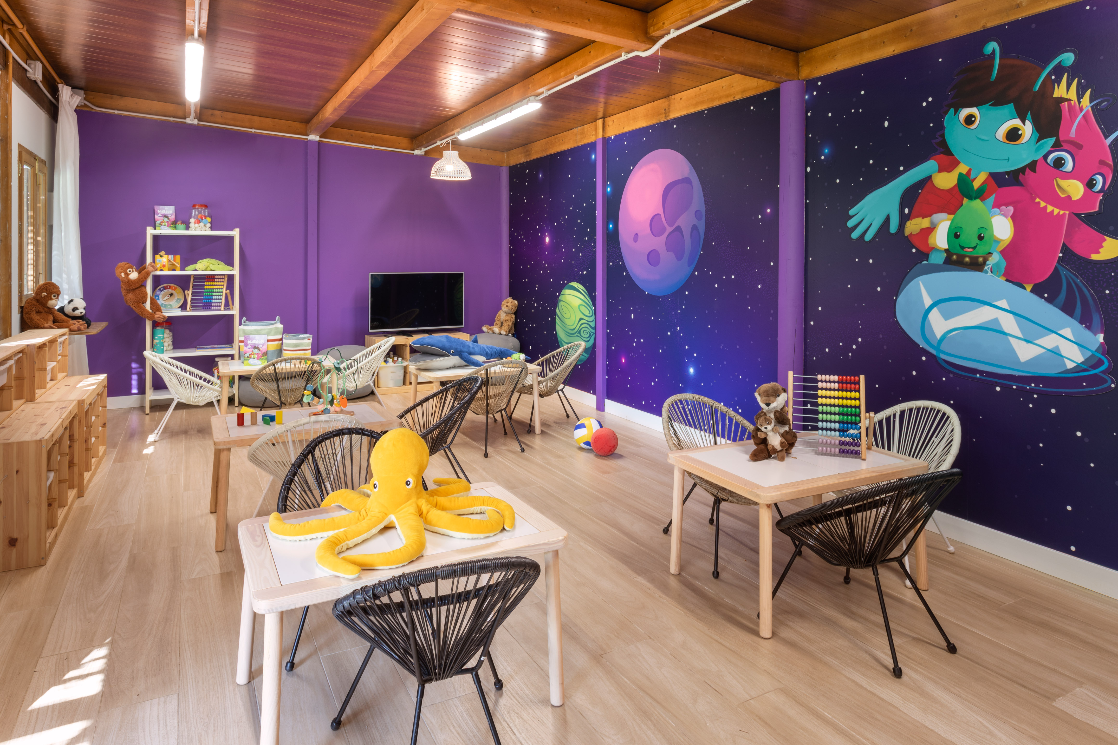 Bright, space-themed kids' playroom with small tables, chairs, and engaging toys.