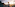 Meditating couple on wooden deck overlooking ocean at sunset.