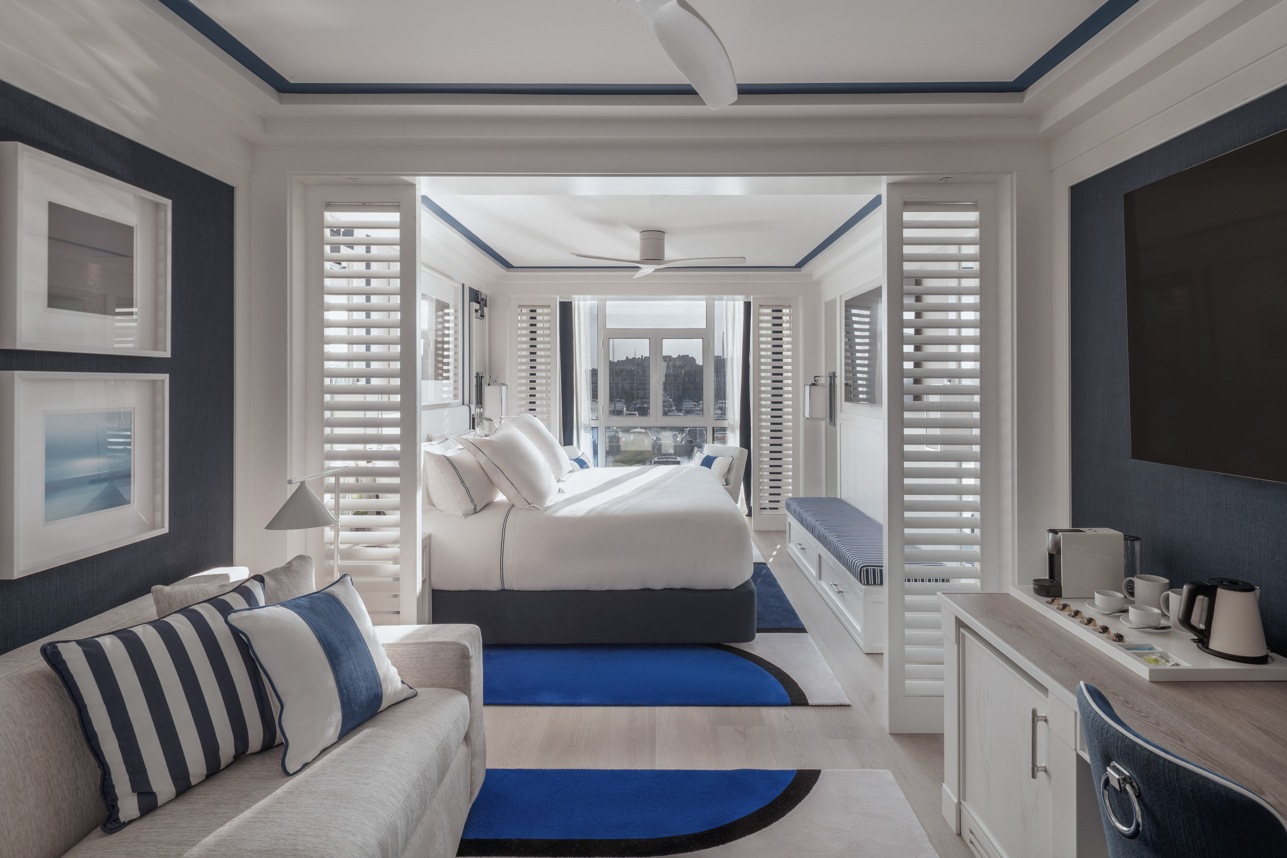 Blue and white hotel suite, large bed, sofa, modern coastal design.