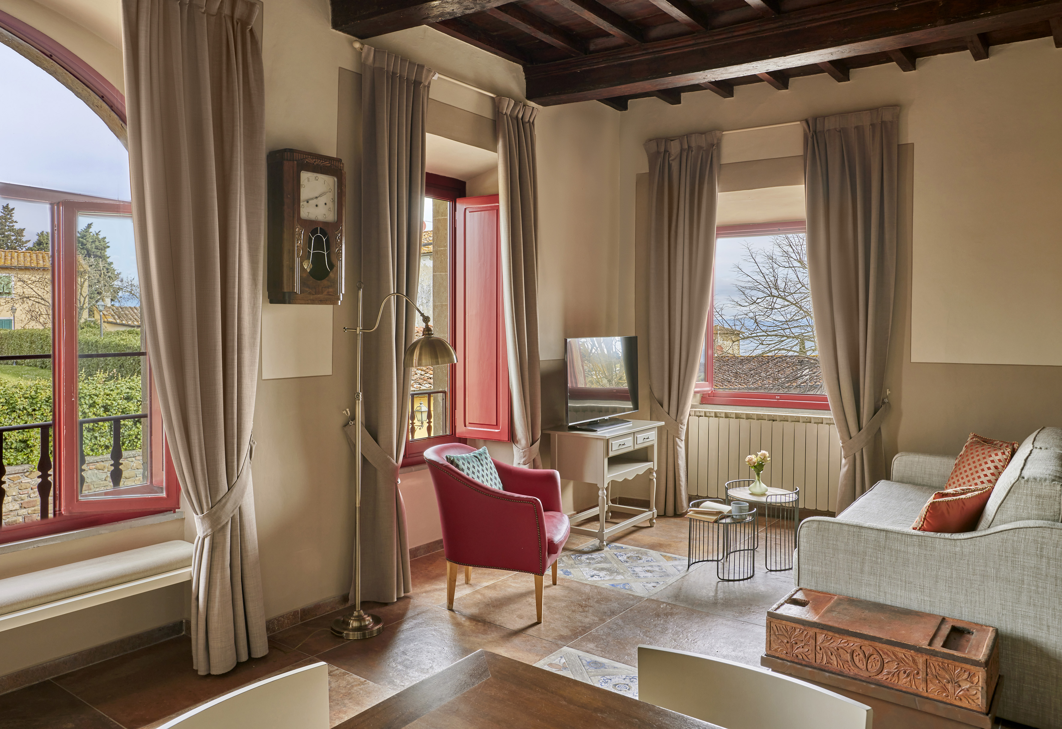 Cozy rustic living room with red armchair, beamed ceiling, and window view.